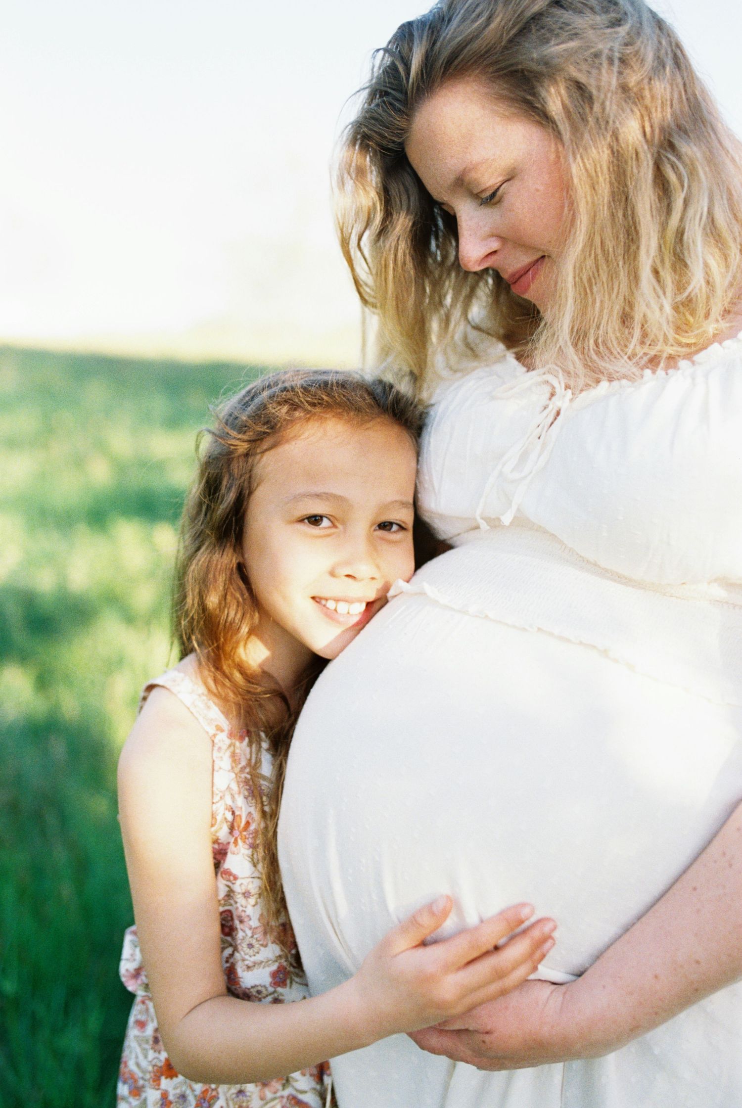 Sweet embrace between child and parent against a sunlit natural backdrop.