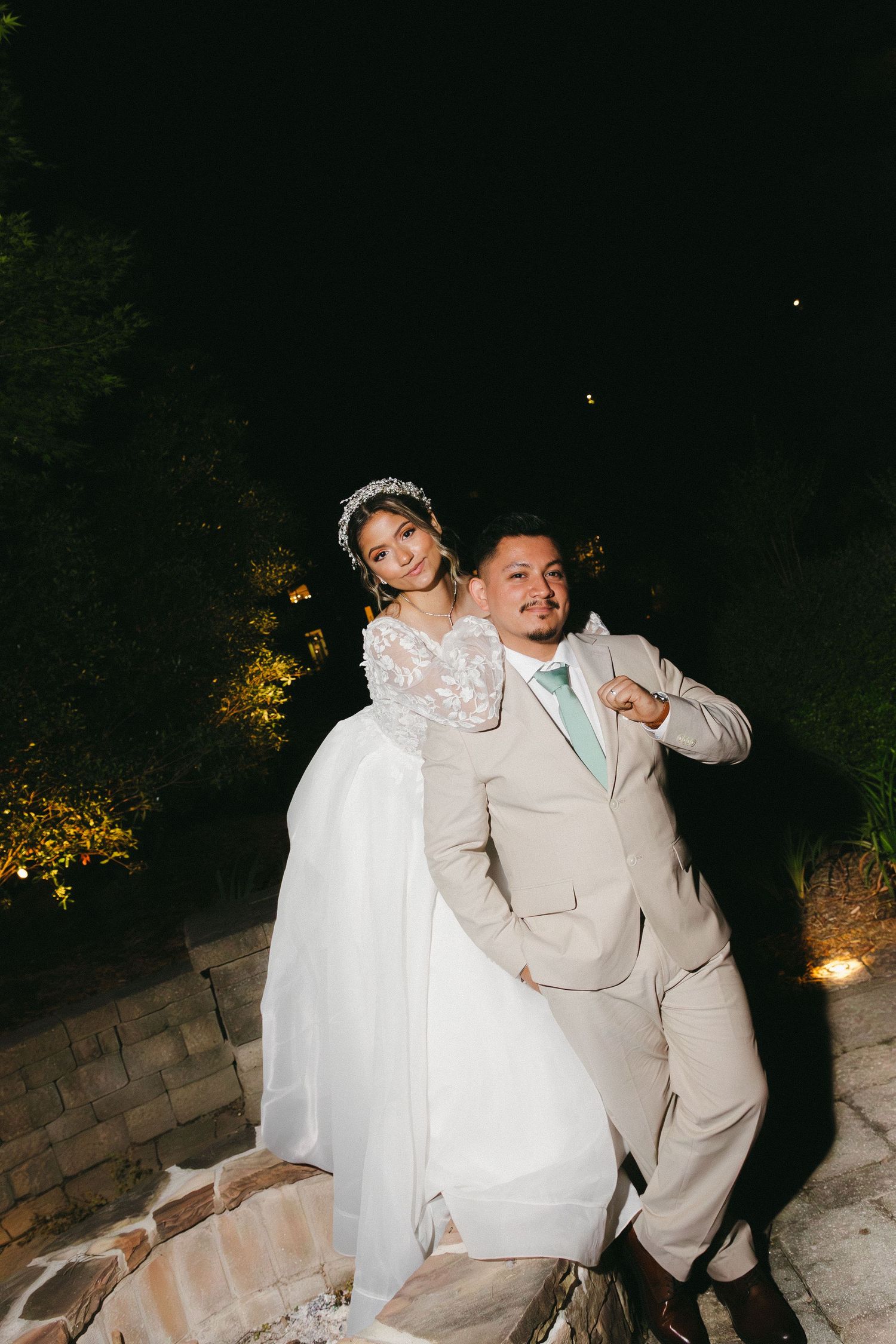 Couple poses playfully on garden steps at dusk during outdoor photoshoot. Cumming, Georgia wedding photographer.