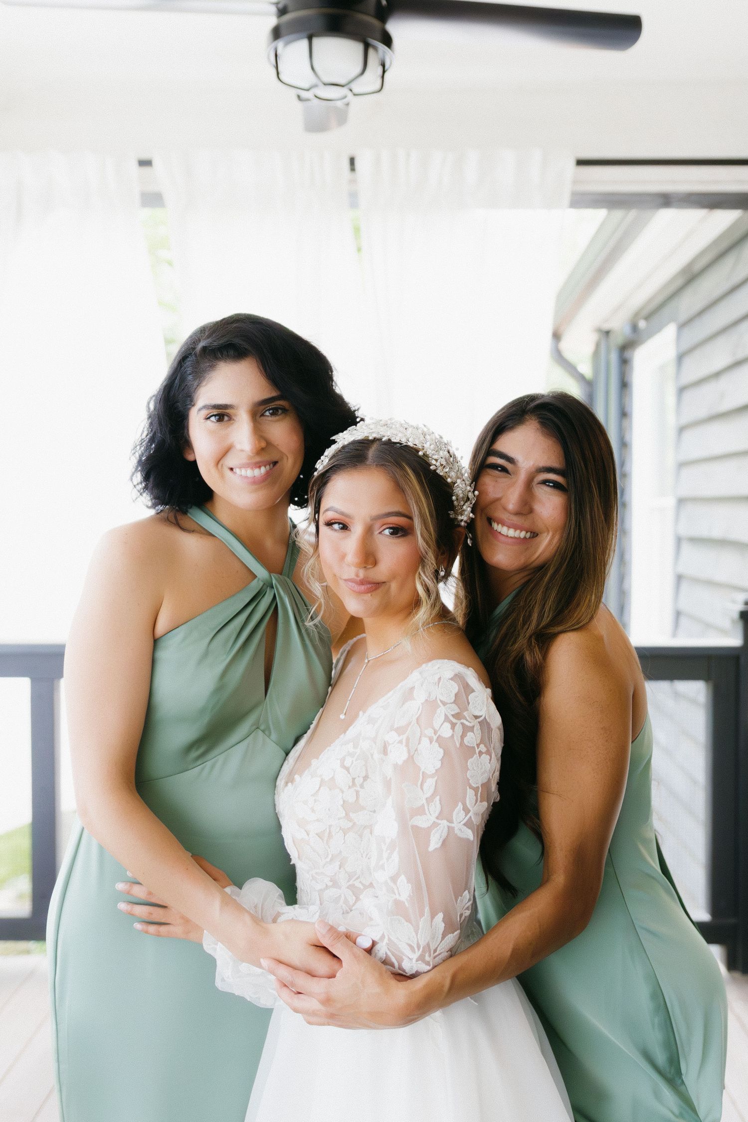 Three women in mint green and white dresses pose together in a bright indoor setting. Cumming, Georgia wedding photographer.