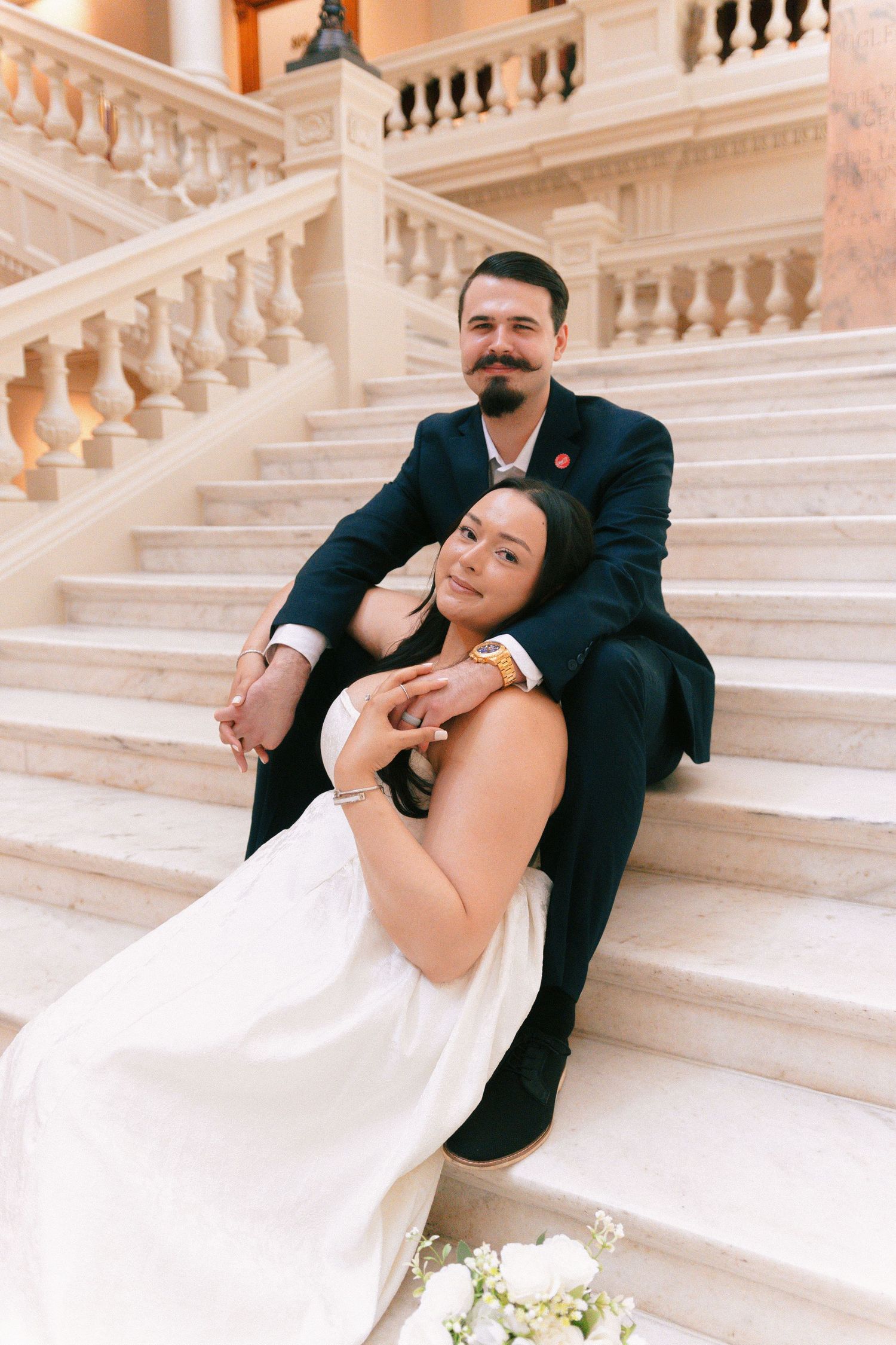 Elegant couple poses romantically on grand marble staircase. Georgia State Capitol wedding photographer.