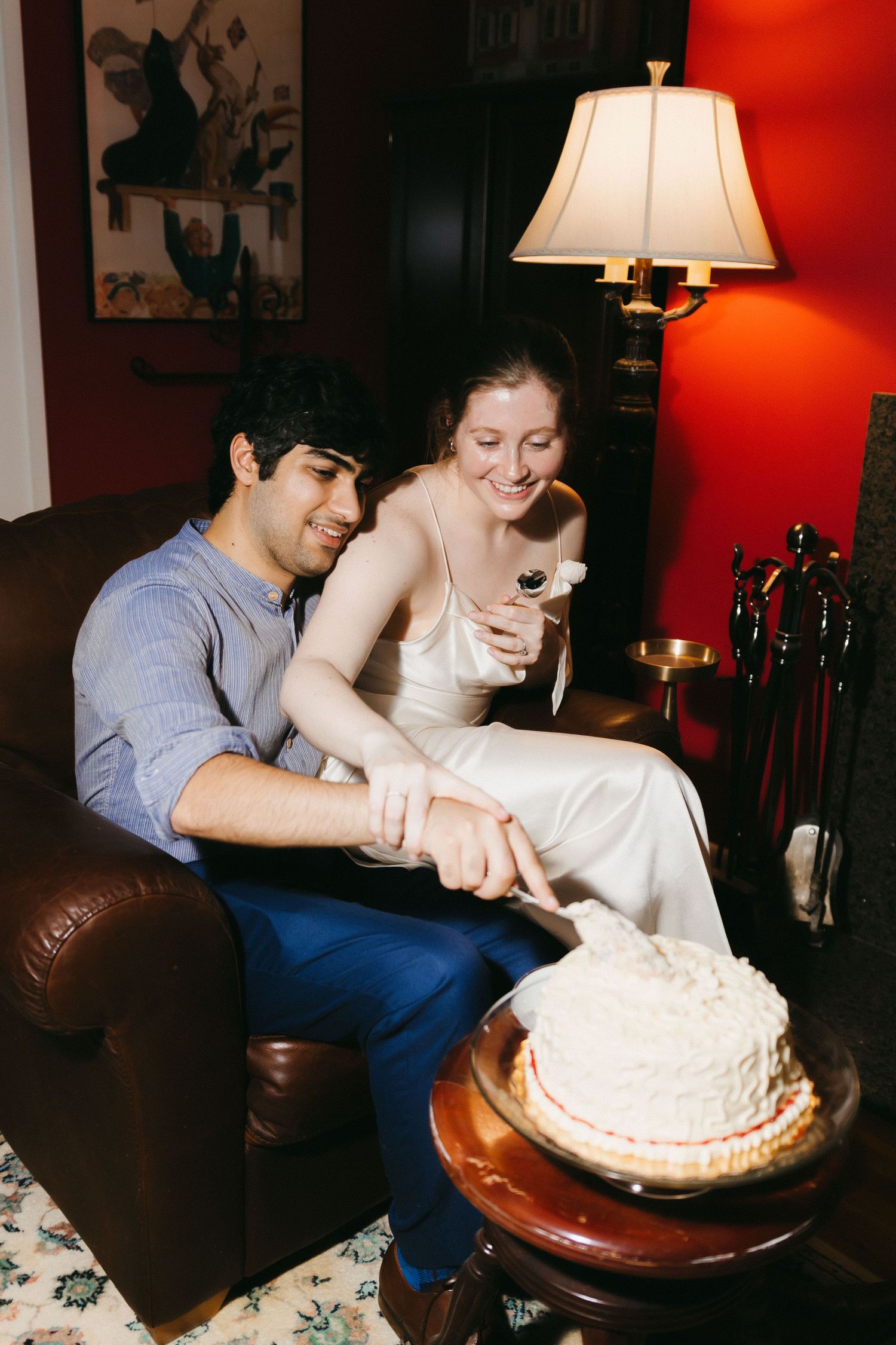 Couple cutting into white wedding cake together in intimate setting. Georgia documentary wedding photographer.