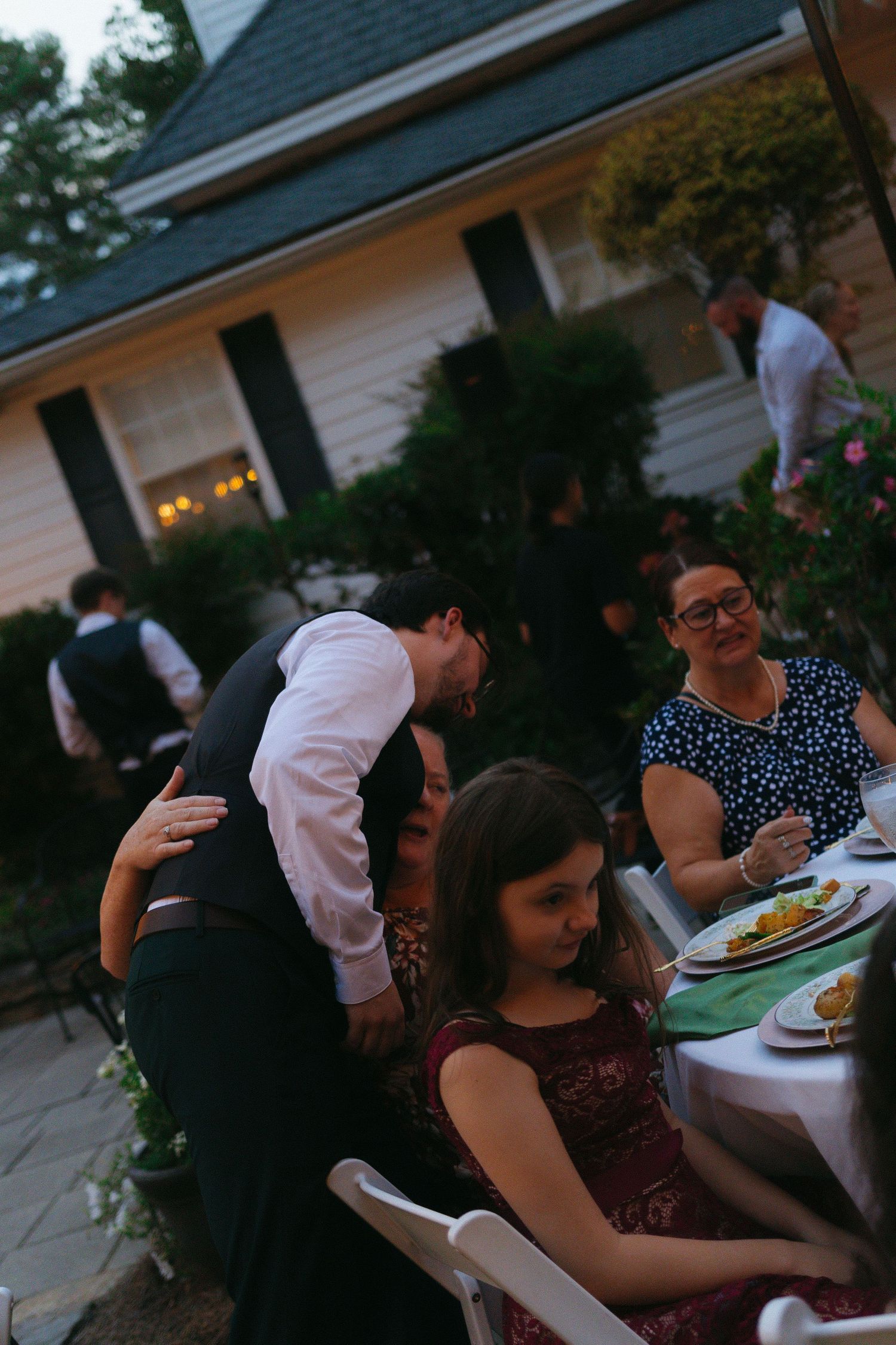 Wedding guests enjoying dinner at outdoor tables during golden hour at a backyard reception. Buford, Georgia wedding photographer.