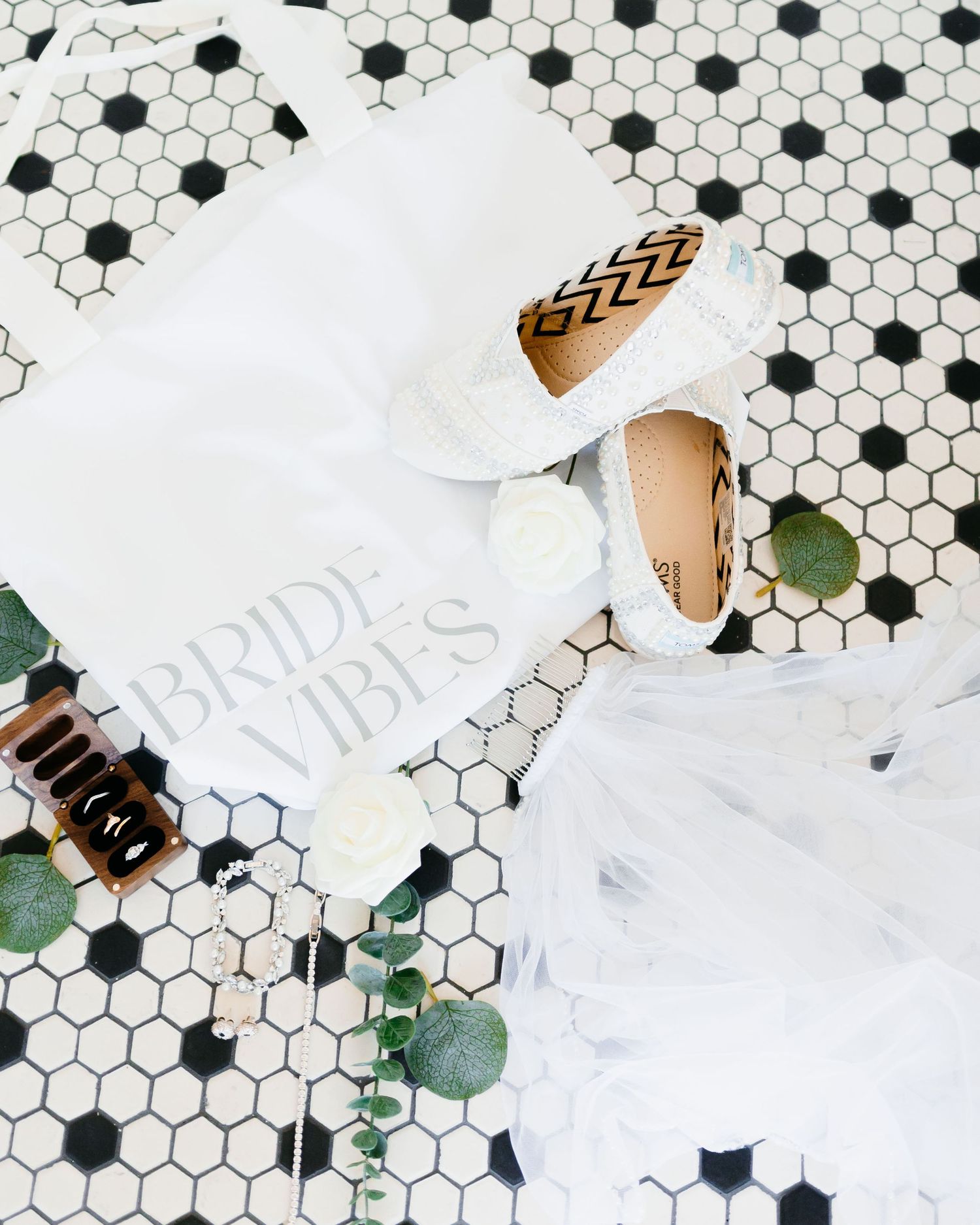 A bridal robe and accessories arranged on black and white hexagon tile flooring. Clarkesville, Georgia wedding photographer.