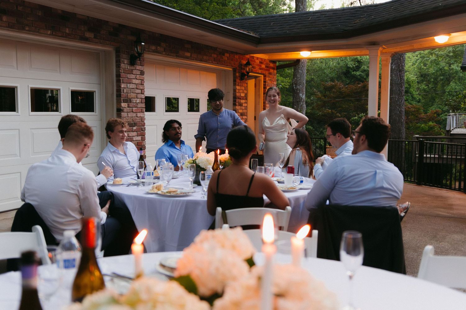 Intimate outdoor wedding reception dinner with guests seated at round tables at dusk. Documentary wedding photographer in Georgia.