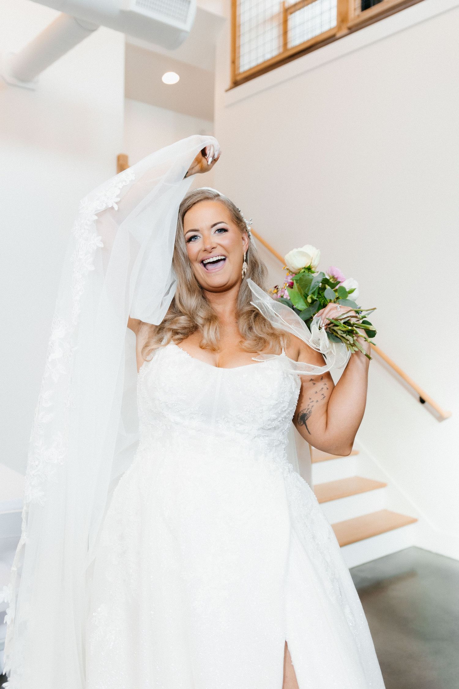 Bride in white wedding dress twirls and laughs joyfully in a bright indoor space. Clarkesville, Georgia wedding photographer.