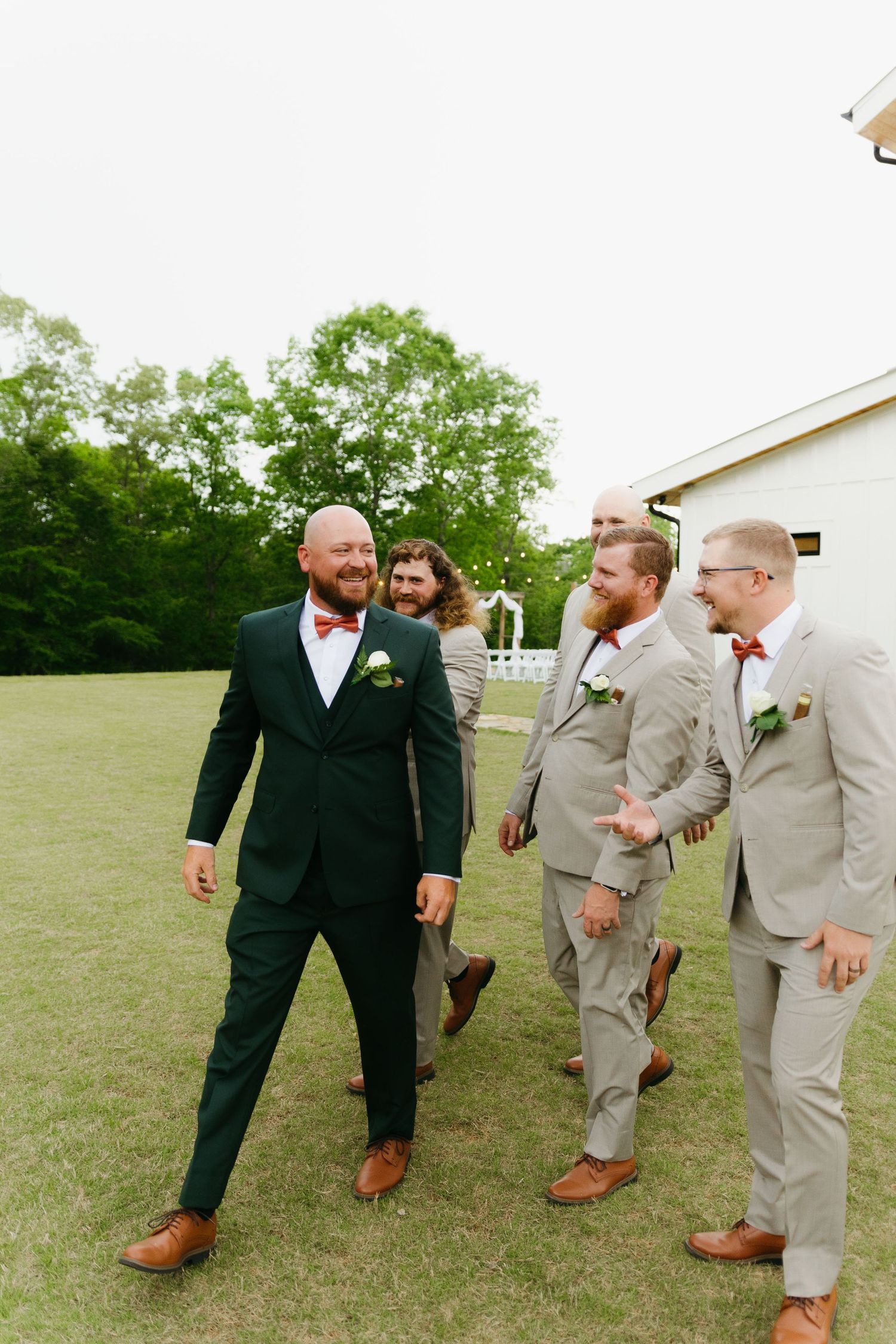 Groomsmen in tan and black suits sharing a casual moment outdoors. Clarkesville, Georgia wedding photographer.
