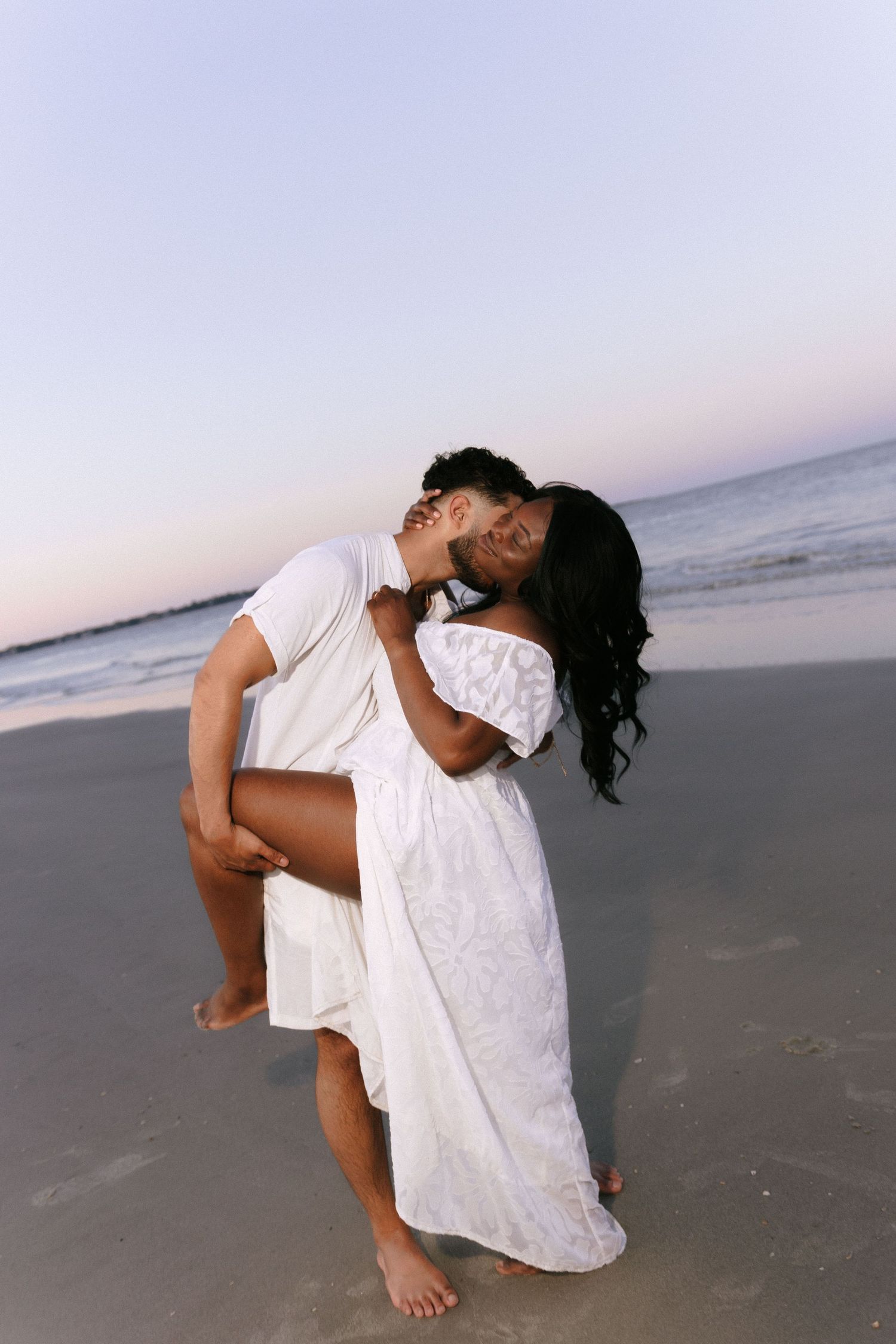 Artistic beach portrait of couple in white creating dynamic poses at sunset. Jekyll island elopement photographer.