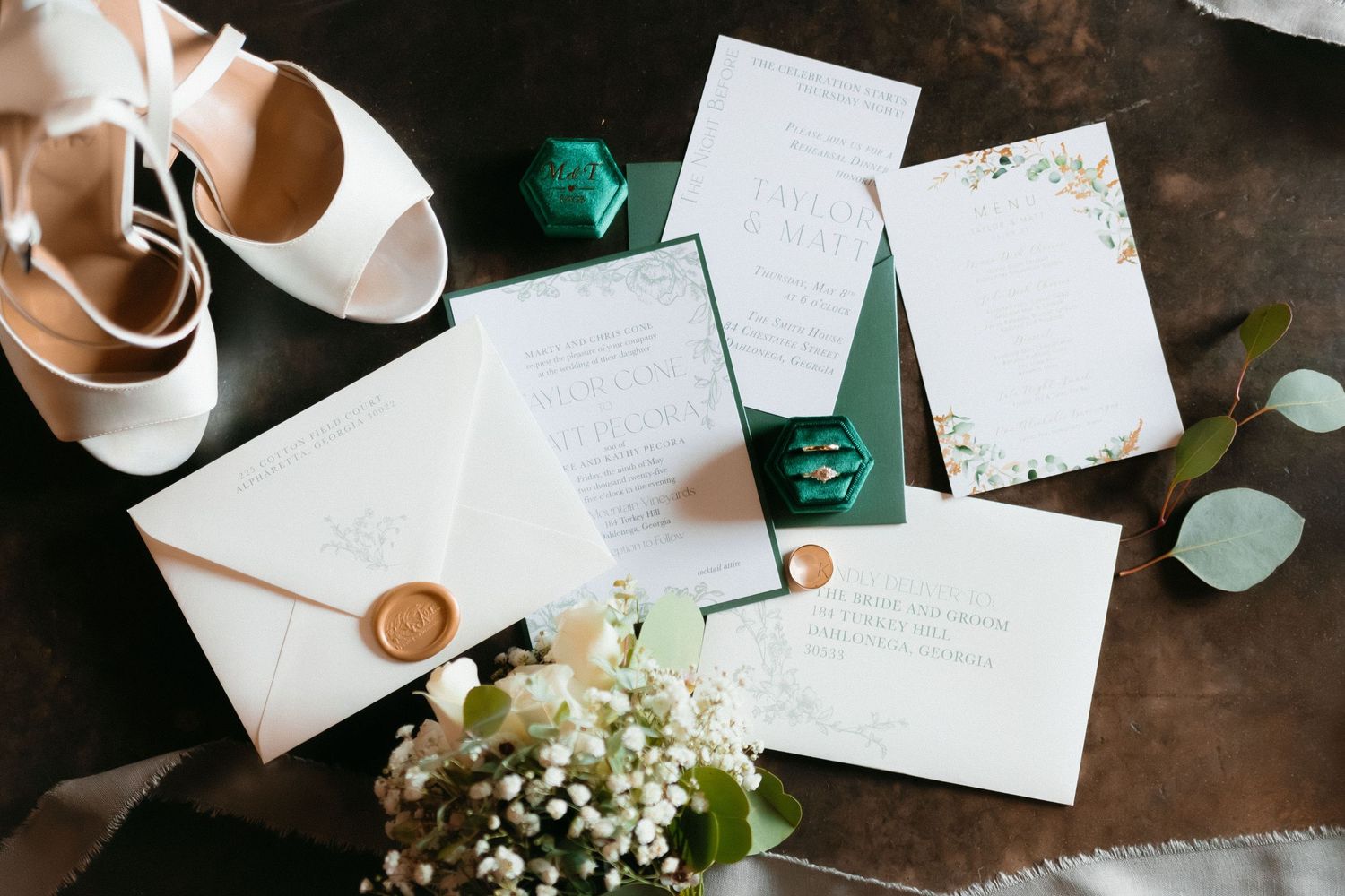 Wedding stationery and invitations displayed on a rustic wooden surface with greenery accents. Dahlonega, Georgia wedding photographer.