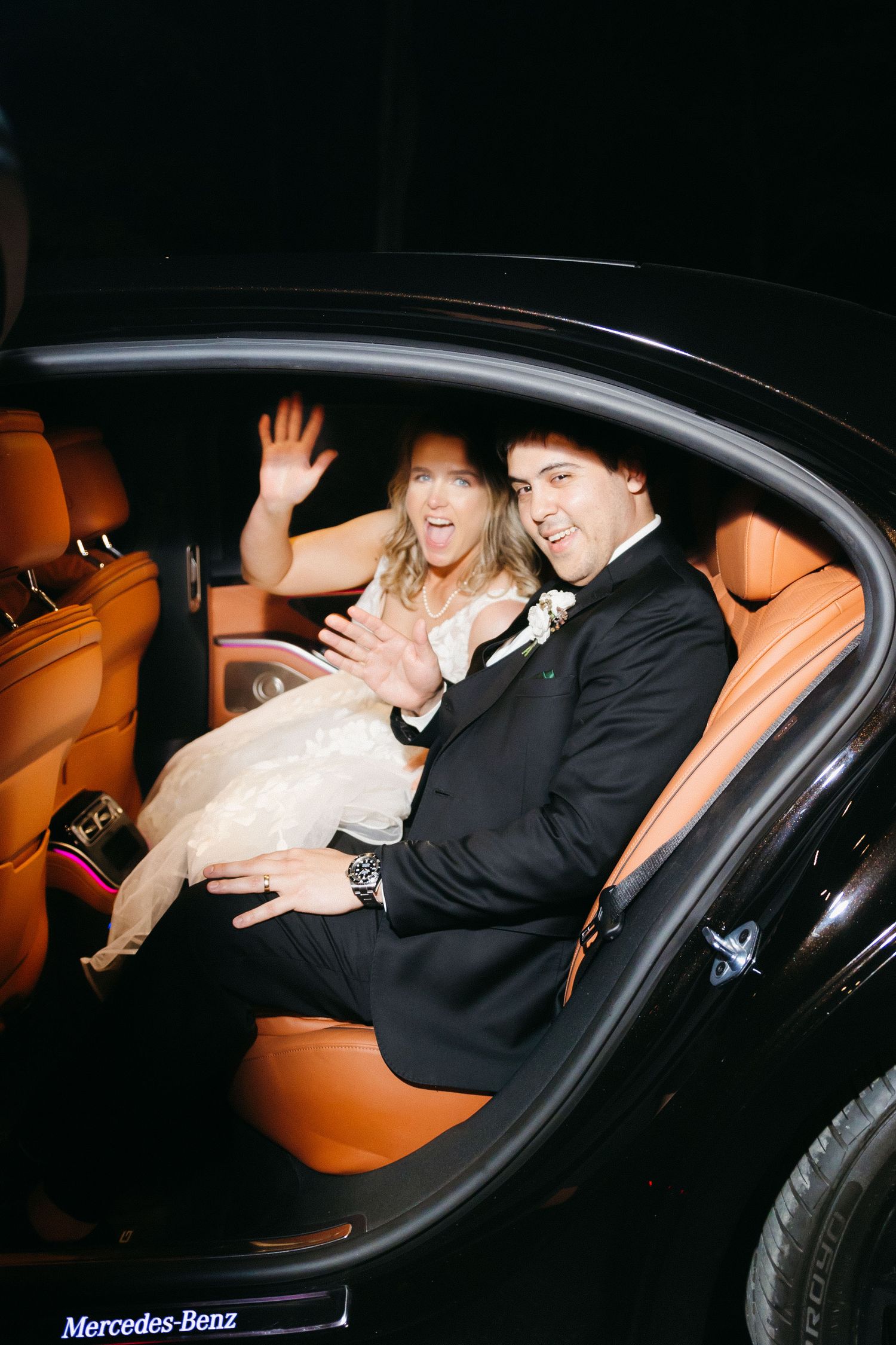 Newlyweds share a joyful moment in the backseat of a luxury Mercedes-Benz car. Blue mountain Vineyards wedding photographer.