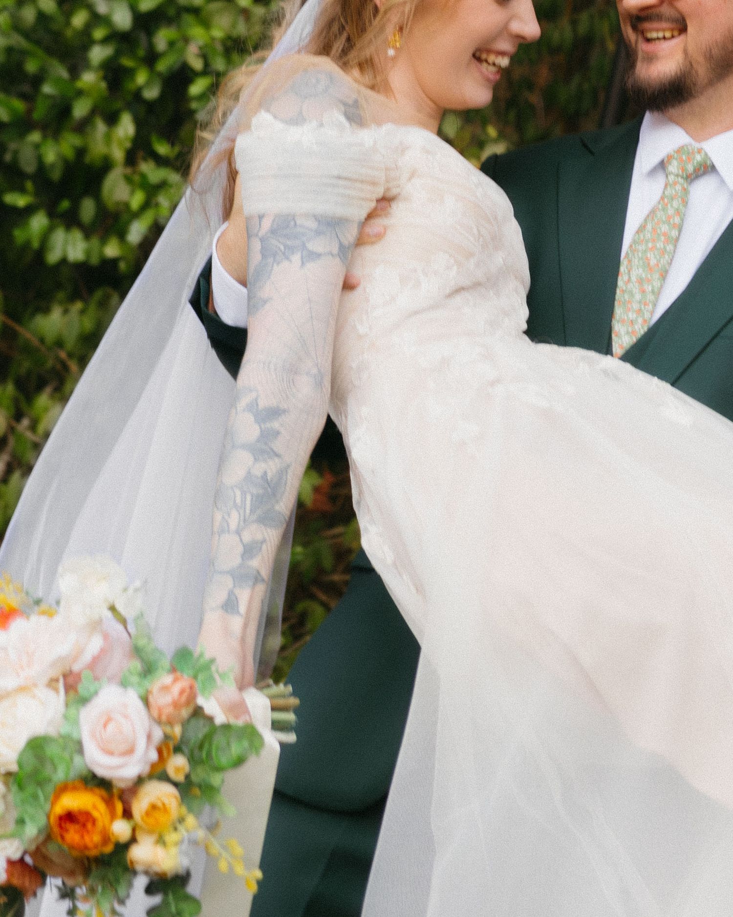 Close-up shot of a couple embracing in wedding attire with a colorful bouquet. Buford, Georgia wedding photographer.