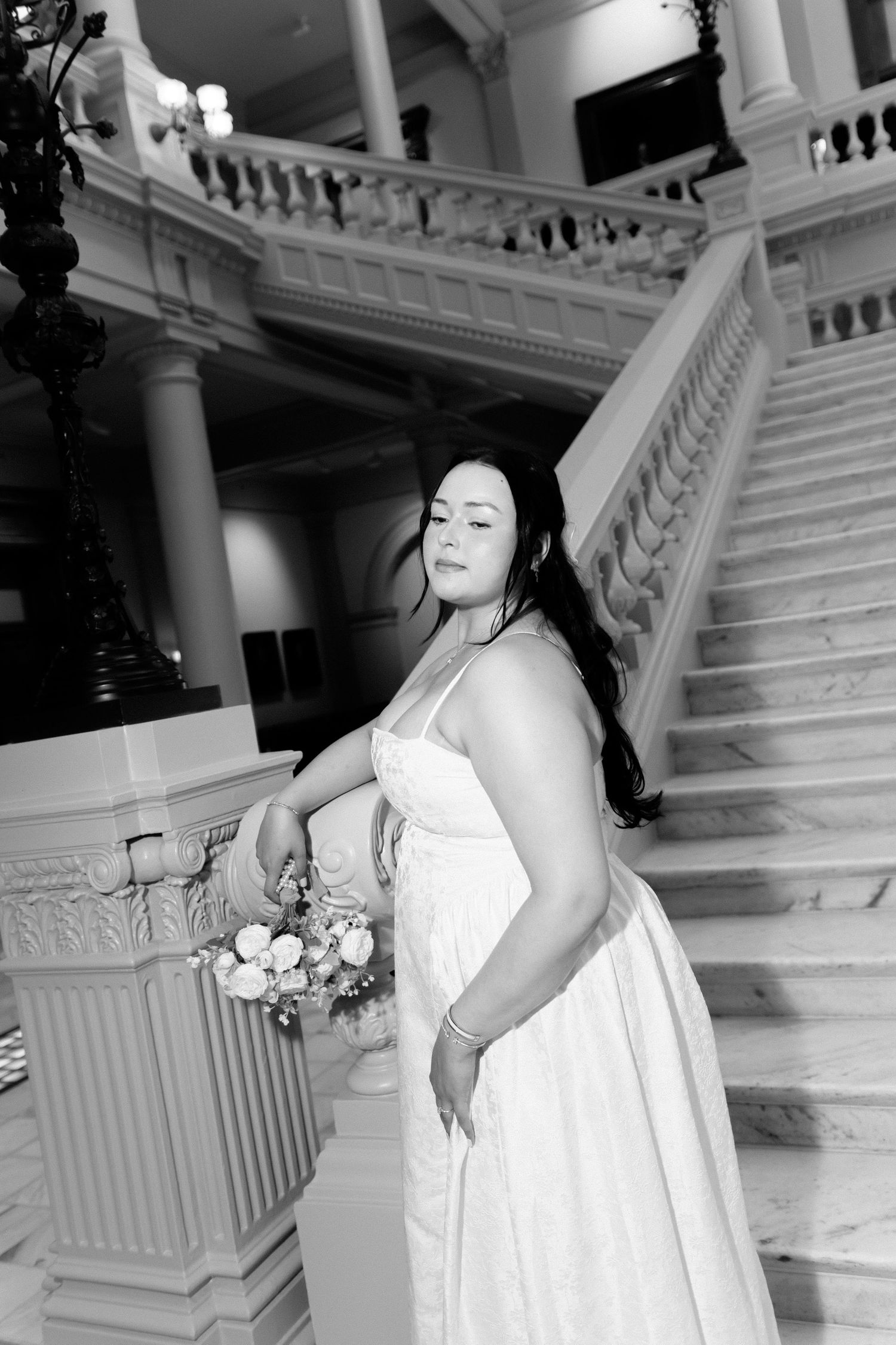 Bride poses on ornate white marble staircase during wedding photoshoot. Georgia State Capitol wedding photographer.