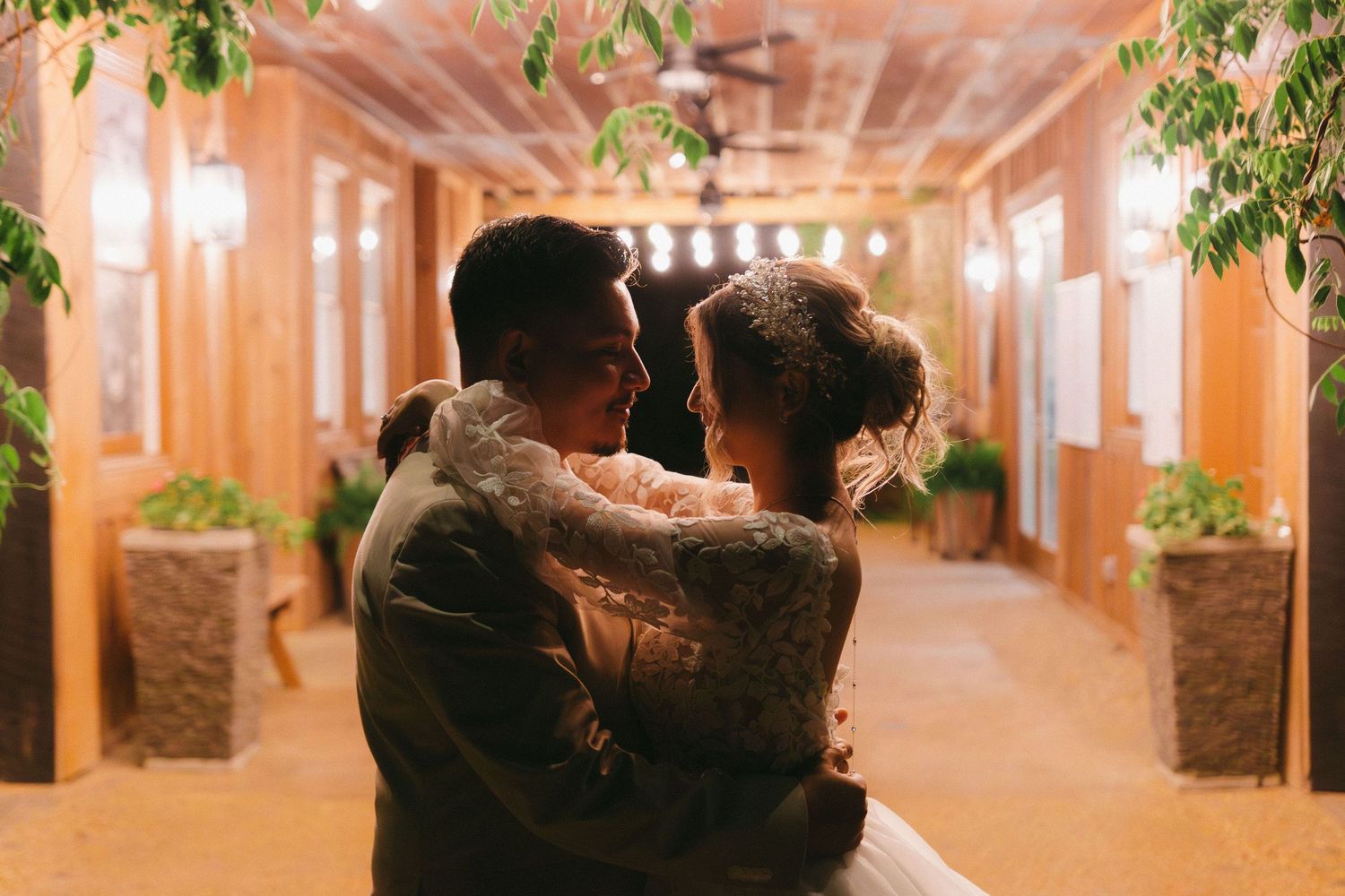 A couple shares an intimate dance moment in an elegantly lit corridor with greenery. Shiloh Gardens wedding photographer.