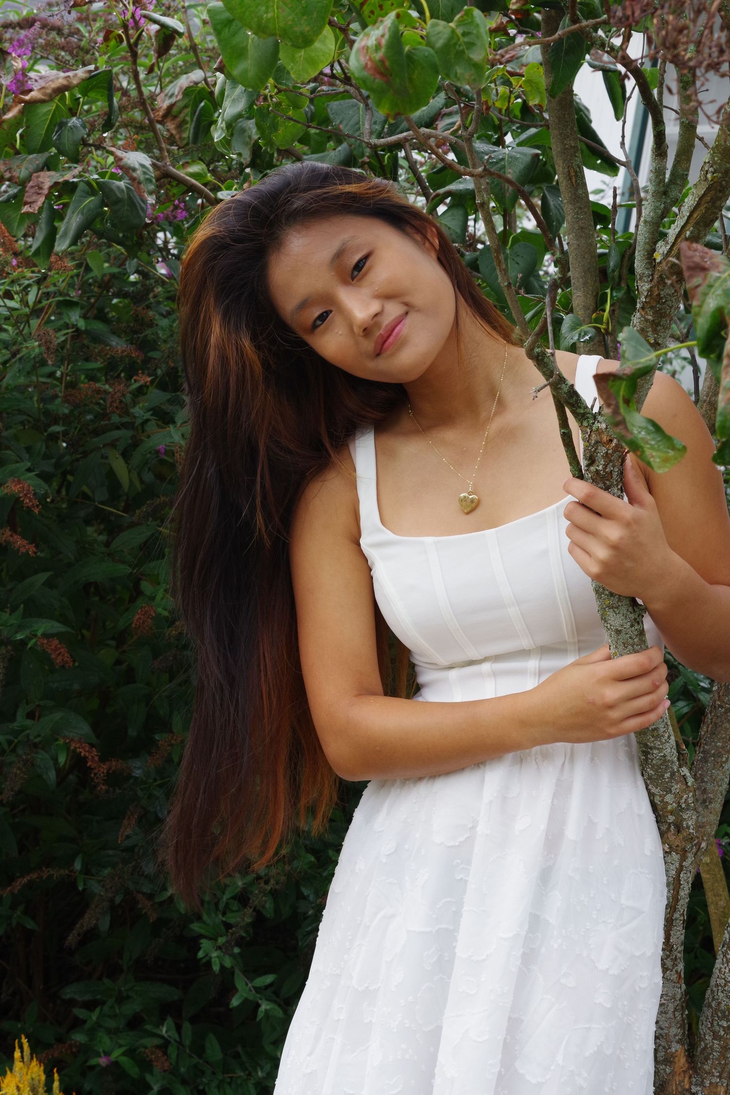 Candid garden portrait in a white summer dress among blooming plants.
