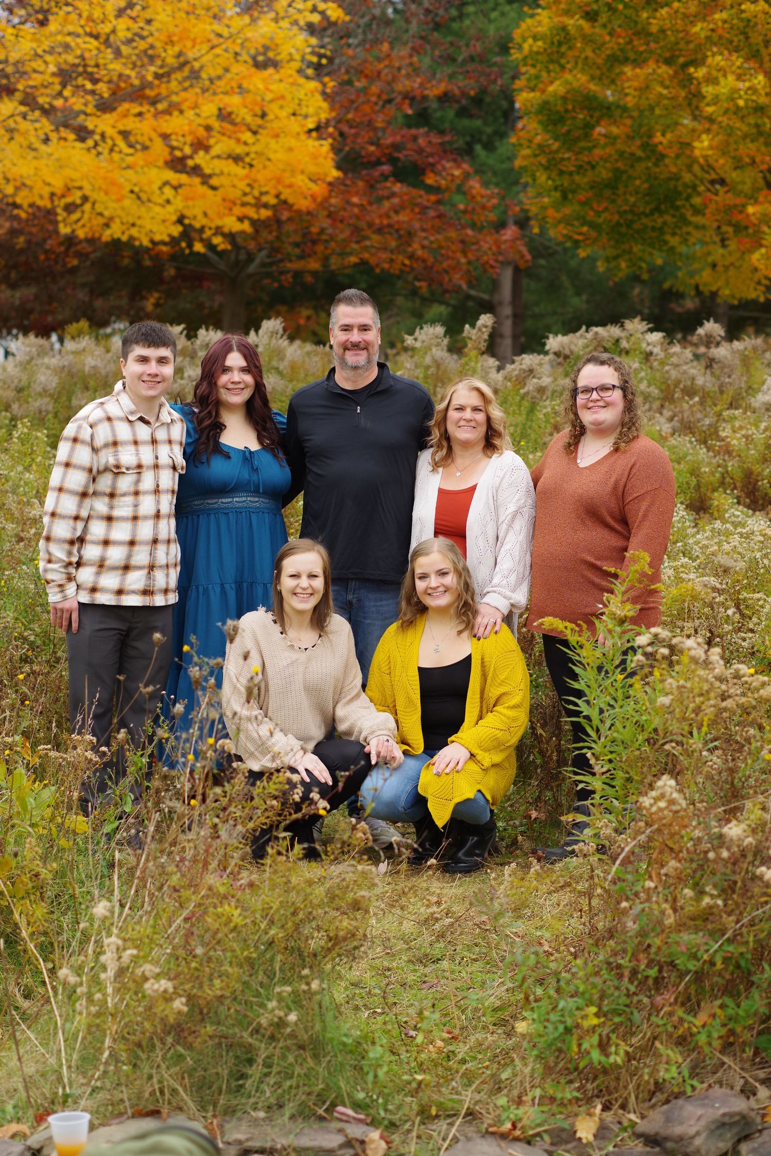 Group portrait in autumn with colorful fall foliage and tall grass in the background.
