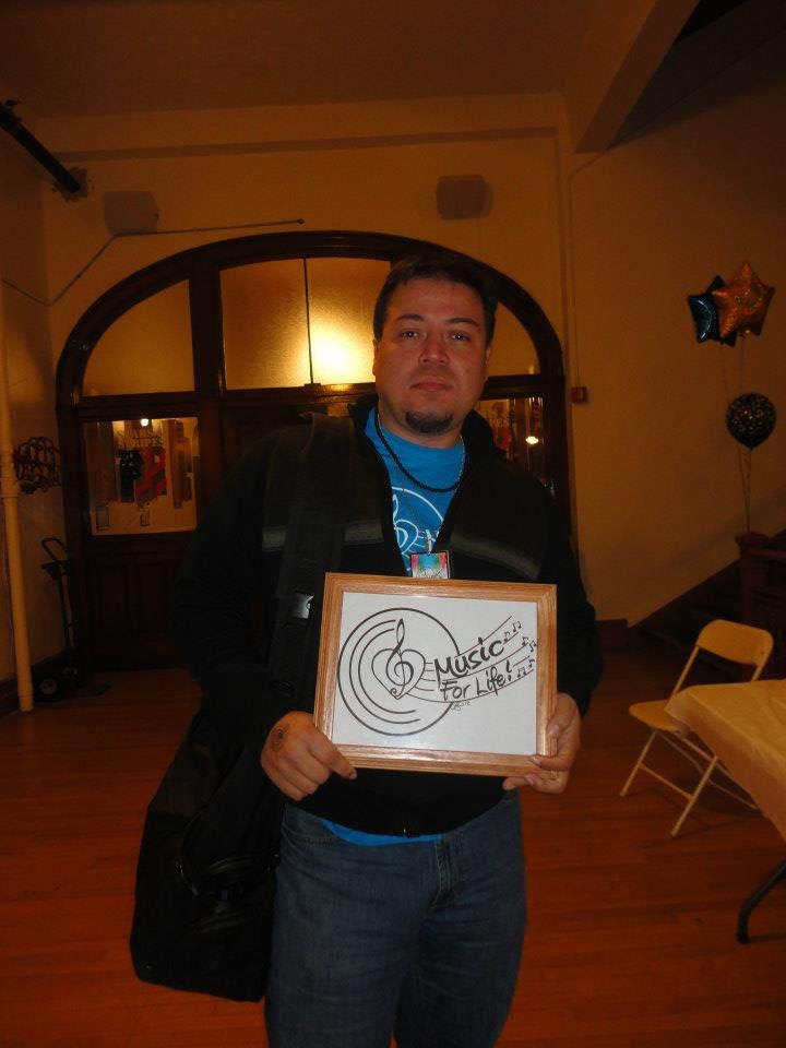 People holding up framed artwork with musical note designs in an indoor venue.