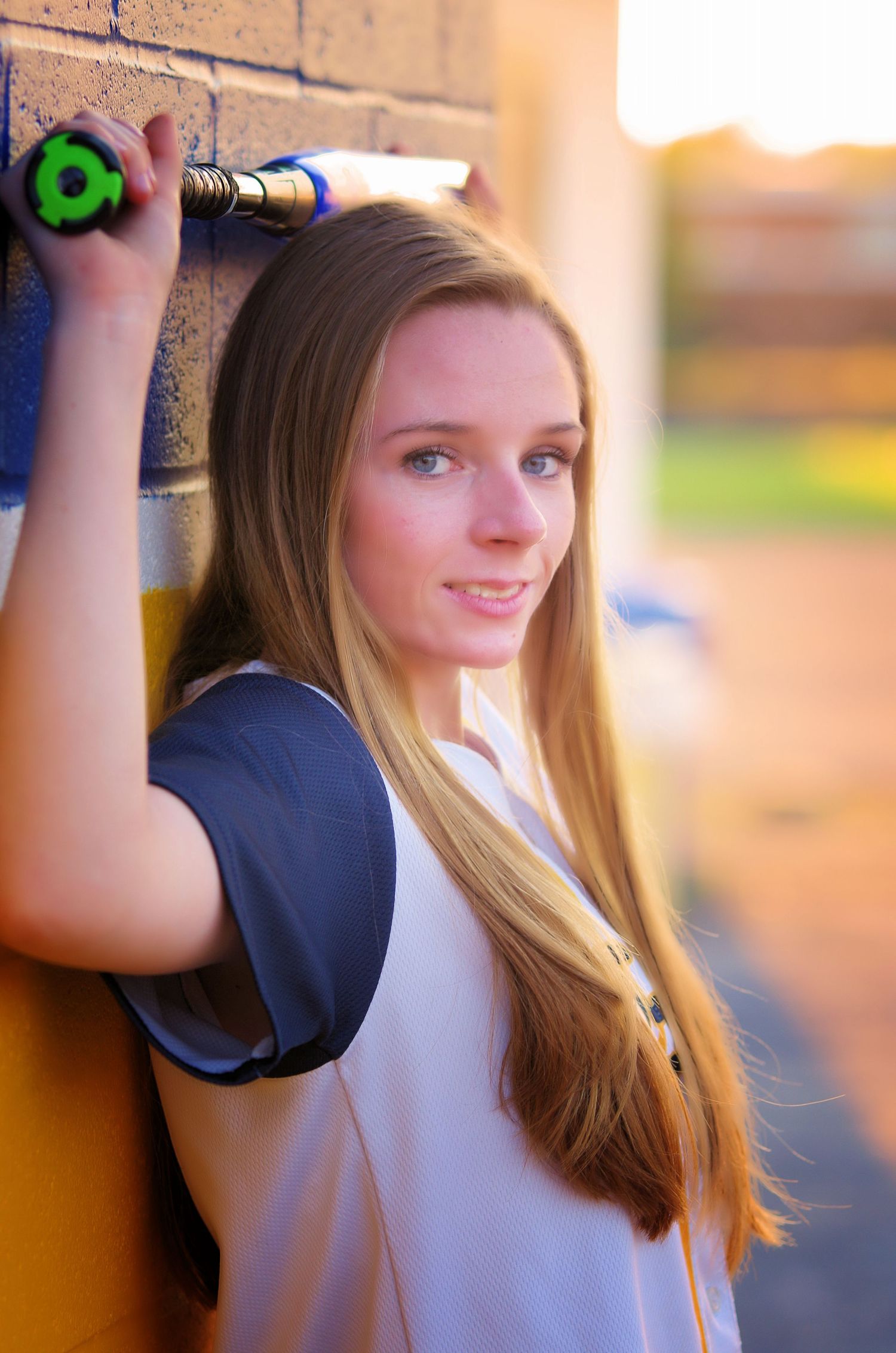 Athletic portrait against colorful wall holding sports equipment at sunset.