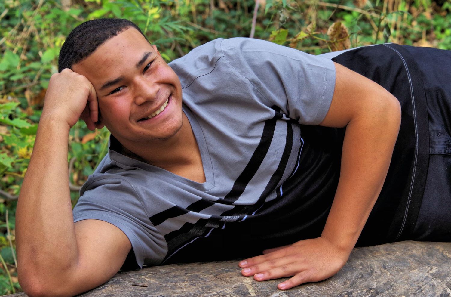 Baseball player resting on concrete surface in casual pose.