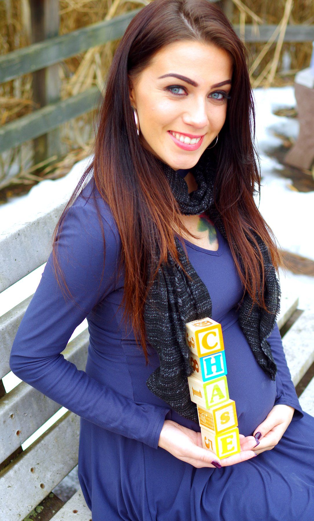 Maternity photo of woman in blue dress holding alphabet blocks.