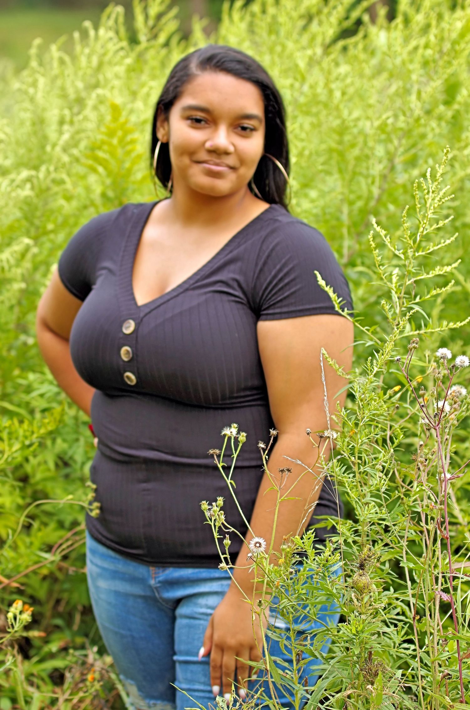 A casual portrait in a lush green meadow with tall grass and wildflowers.