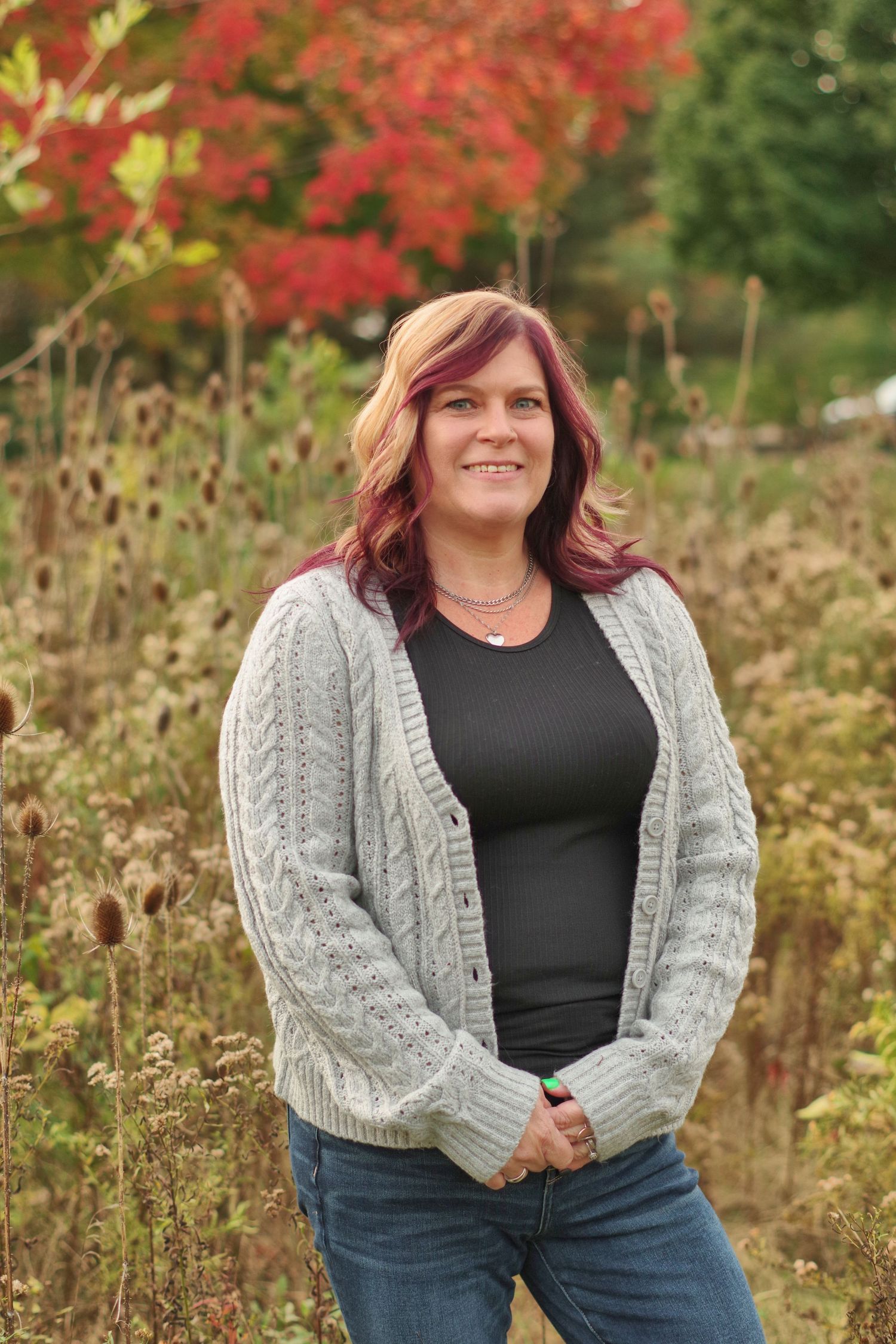 Fall outdoor portrait with gray cardigan against natural autumn backdrop with red leaves.