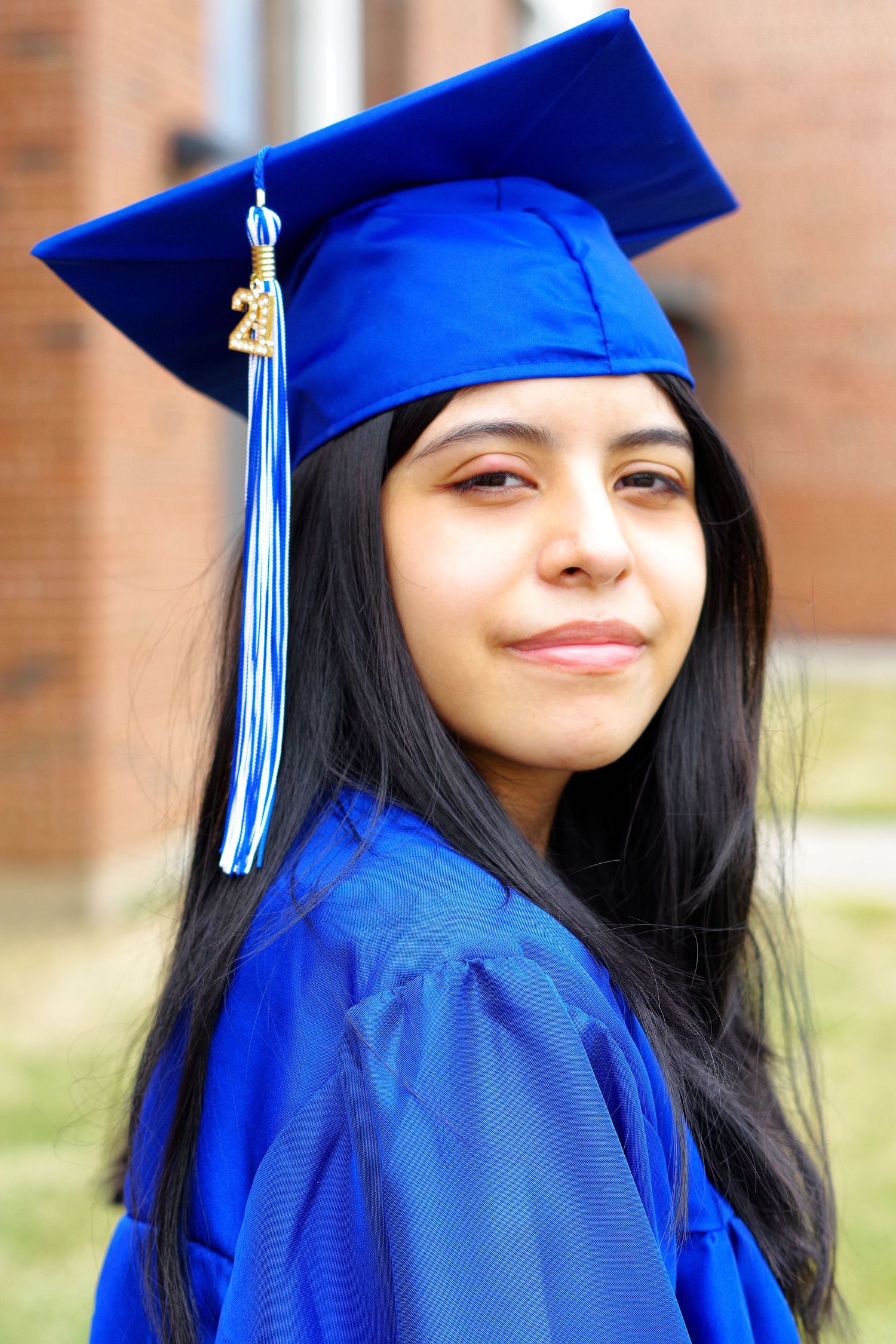 Candid graduation portraits showing joyful expressions in bright blue cap and gown.