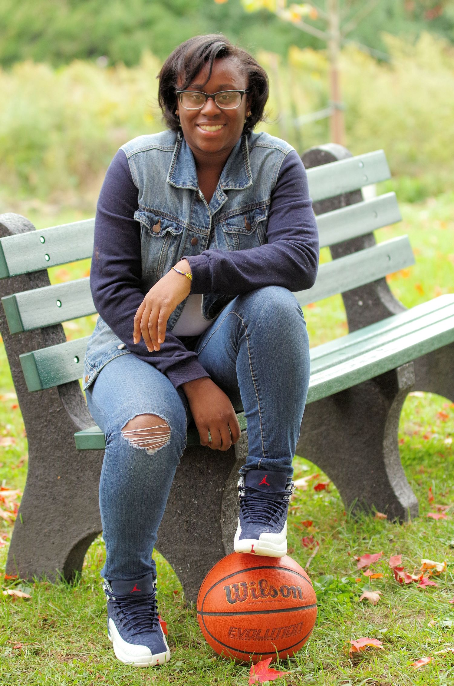 Casual portrait on park bench with basketball and ripped jeans.