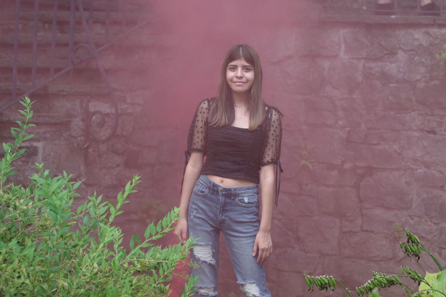 Fashion portrait against brick wall wearing black lace top and distressed jeans.