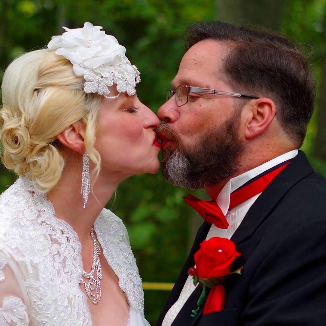 Wedding couple sharing intimate moments in formal attire with red accents.