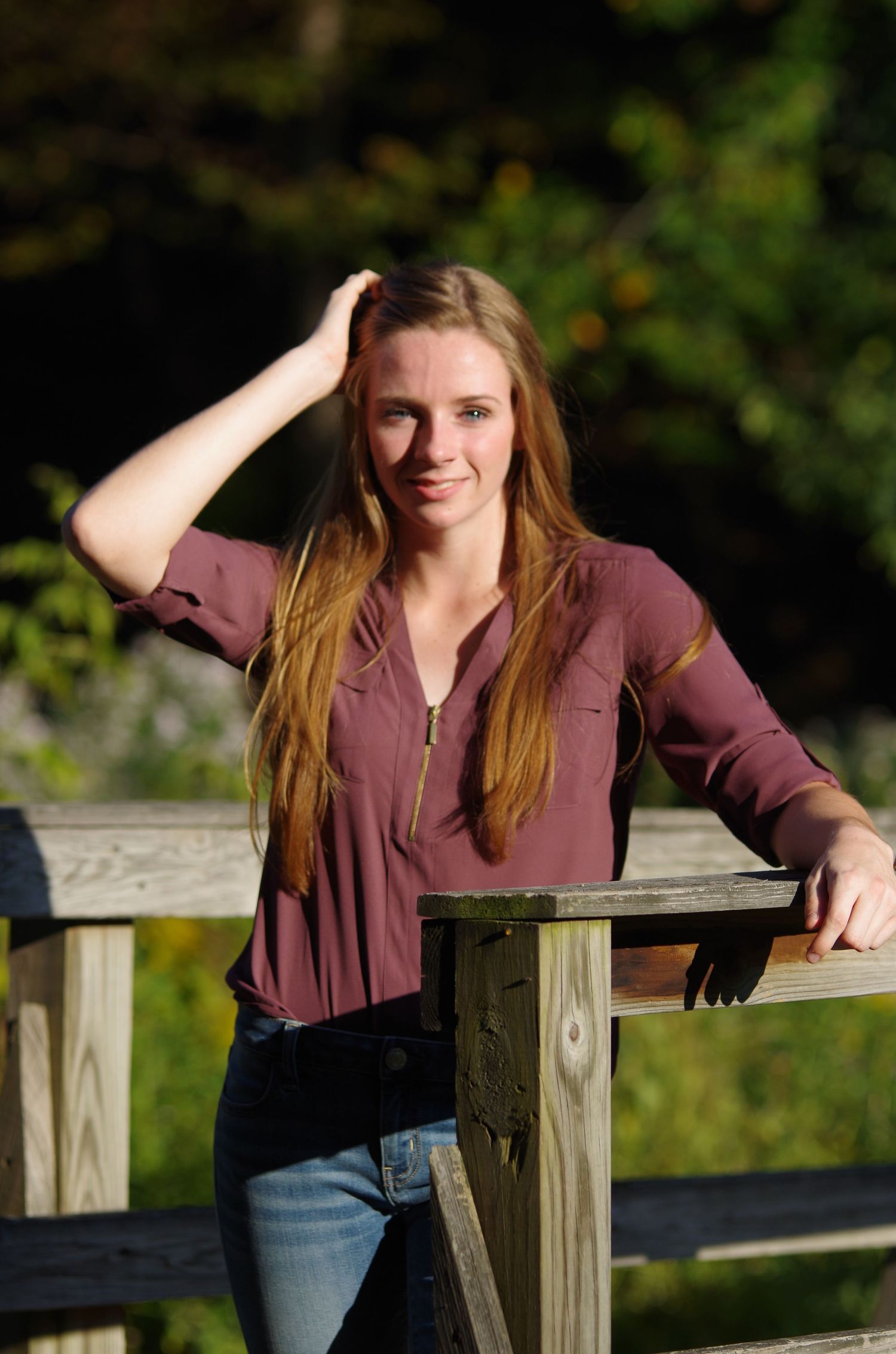 Casual pose leaning on wooden fence during sunset photoshoot.