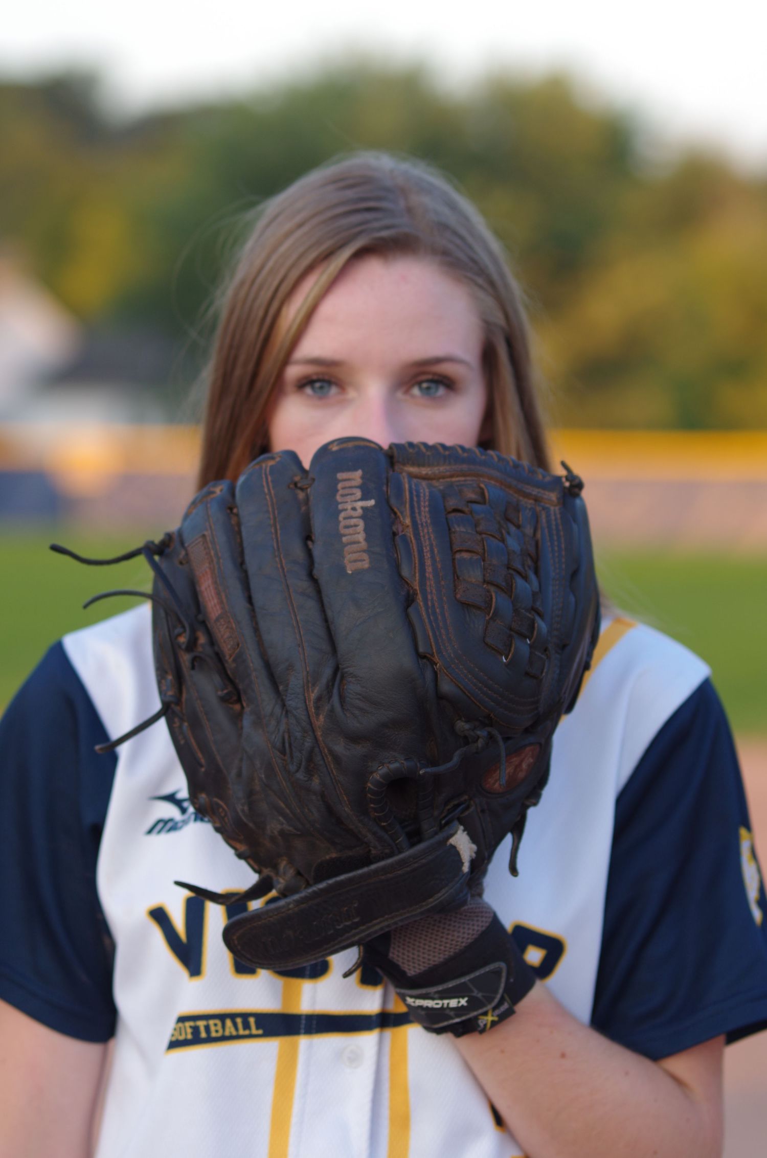 Close-up sports portrait with baseball glove held up near face.