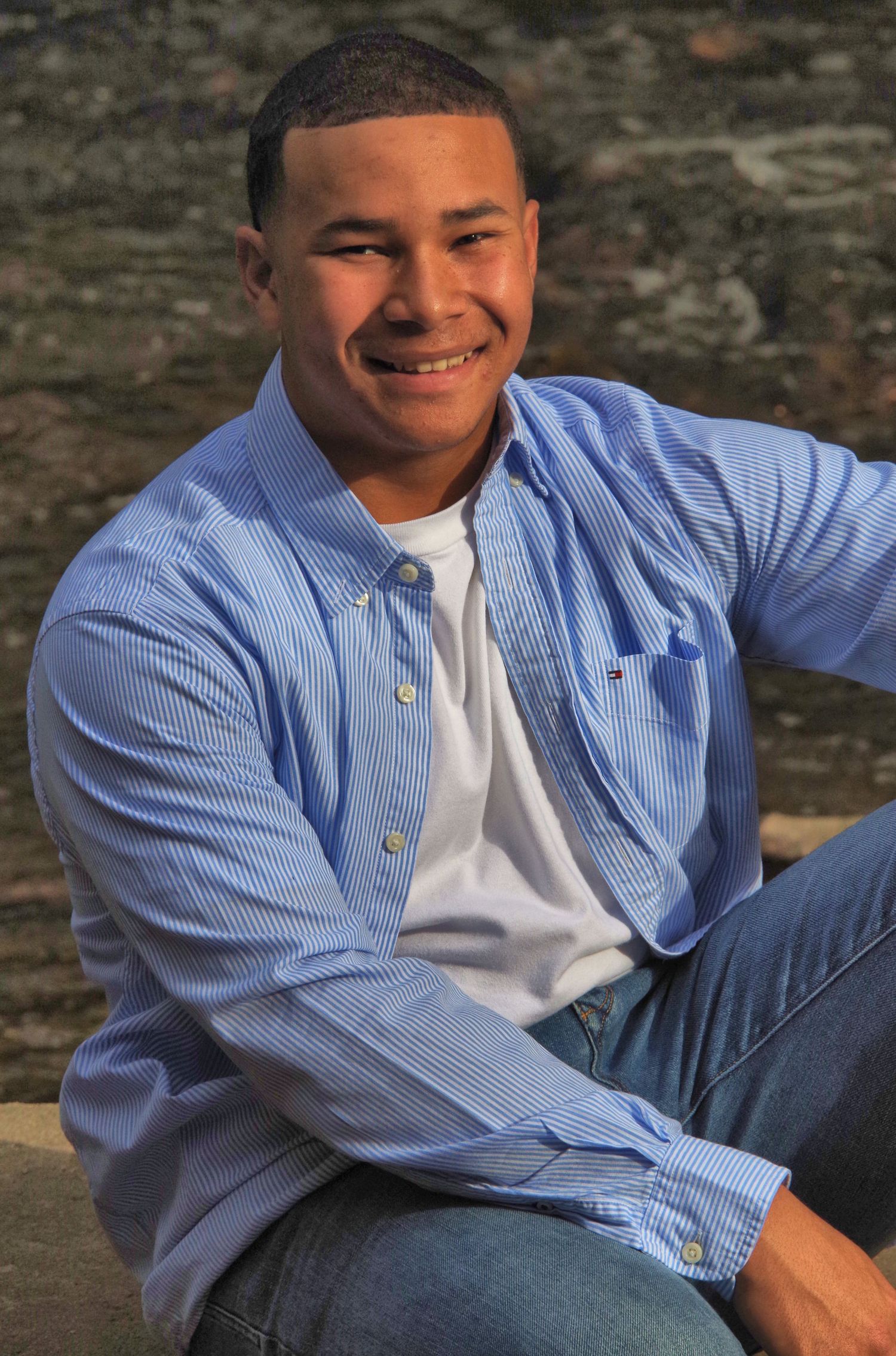 Person in blue striped button-down shirt sitting casually outdoors.