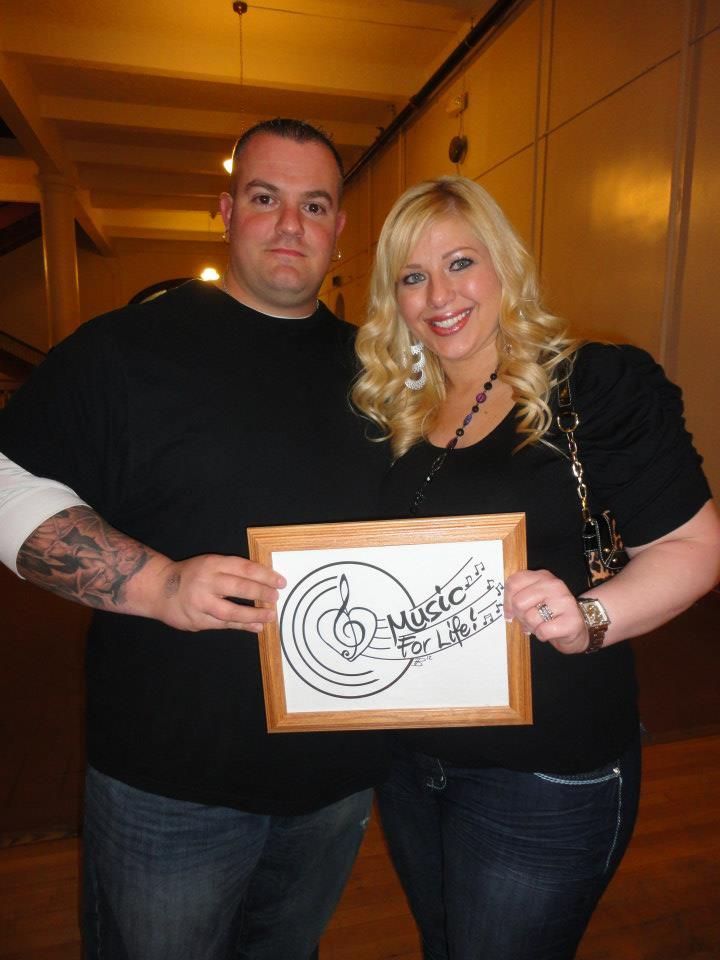 Event participants displaying identical framed musical artwork in a community hall setting.
