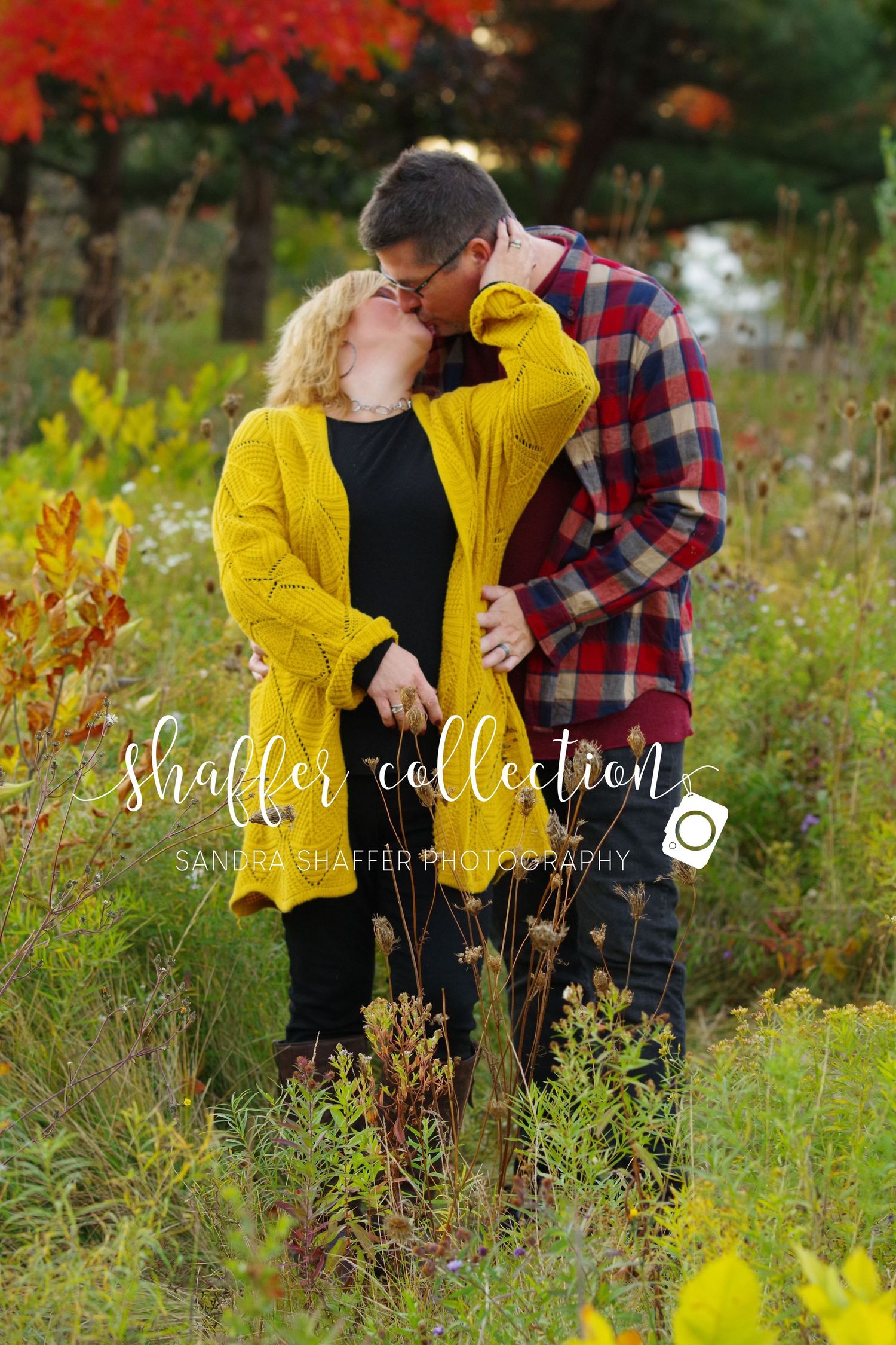 A romantic moment captured in a field with fall foliage and yellow wildflowers.