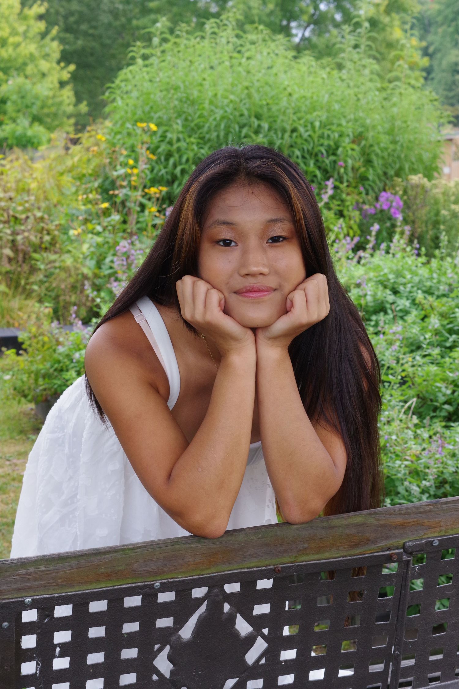 Casual outdoor portrait resting on wooden bench in garden setting.