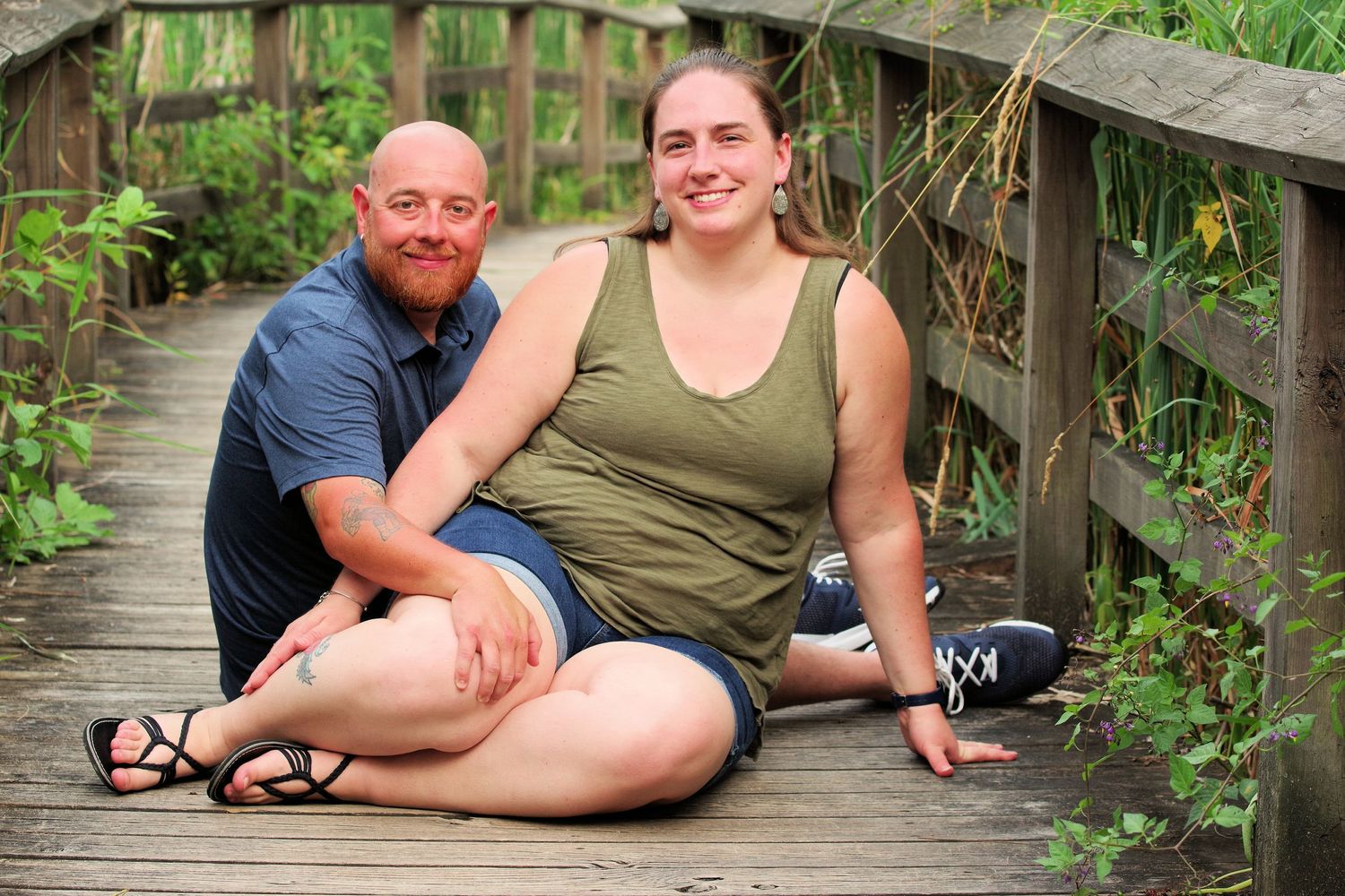 Outdoor portrait on a wooden boardwalk surrounded by greenery.