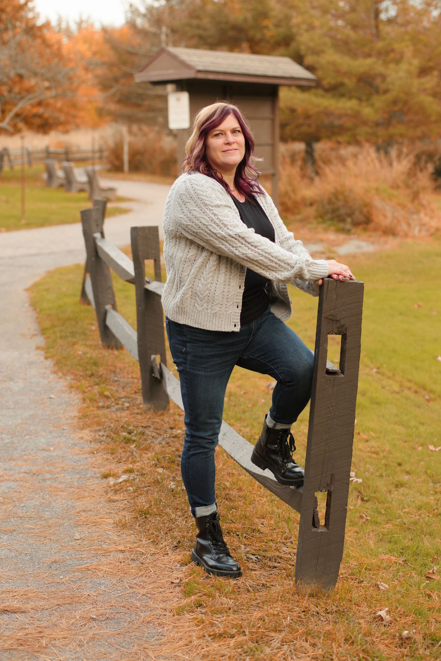 Person stretching on wooden fence during autumn photoshoot.