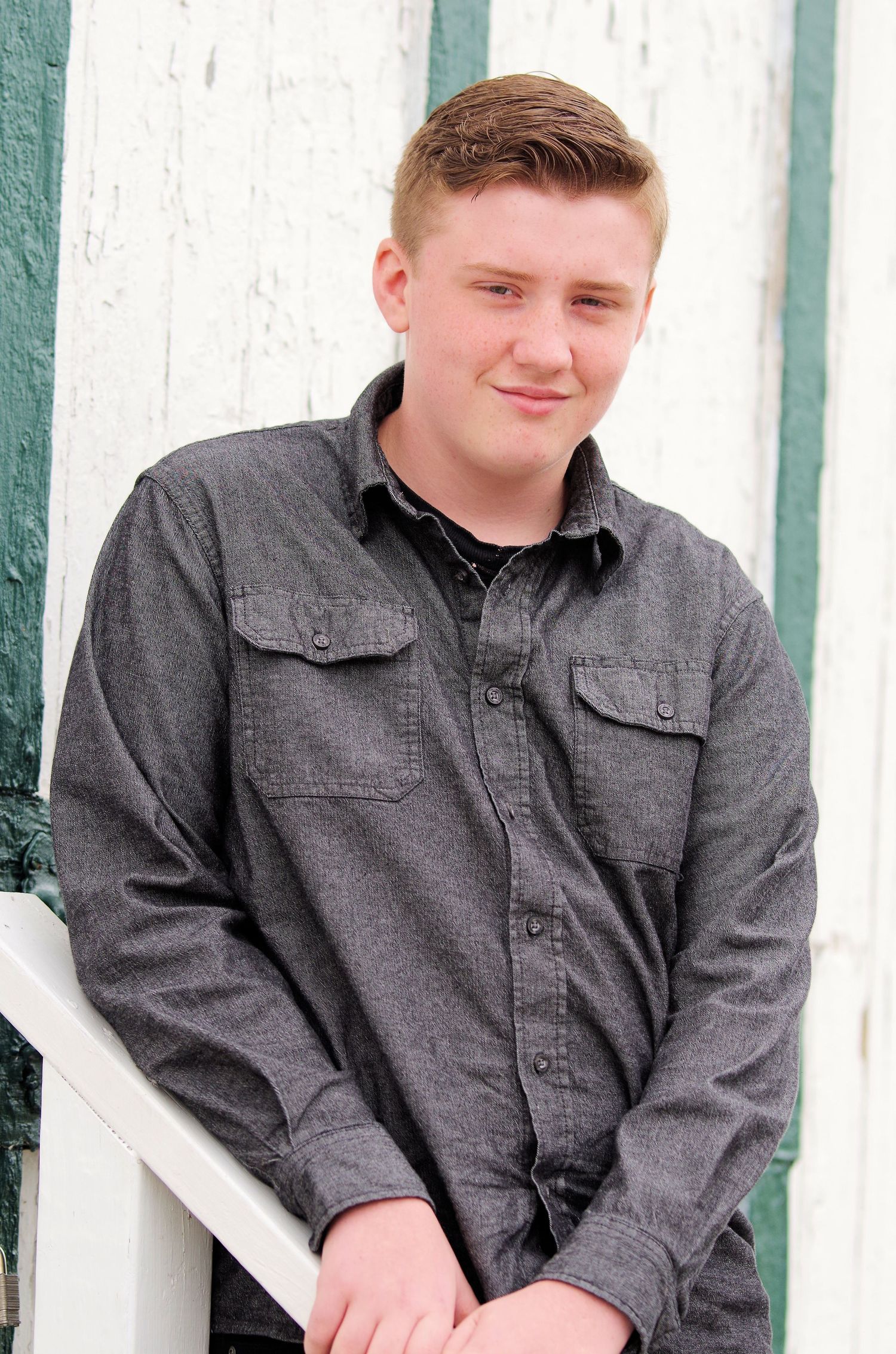 Portrait against white wall wearing gray casual button-down shirt.