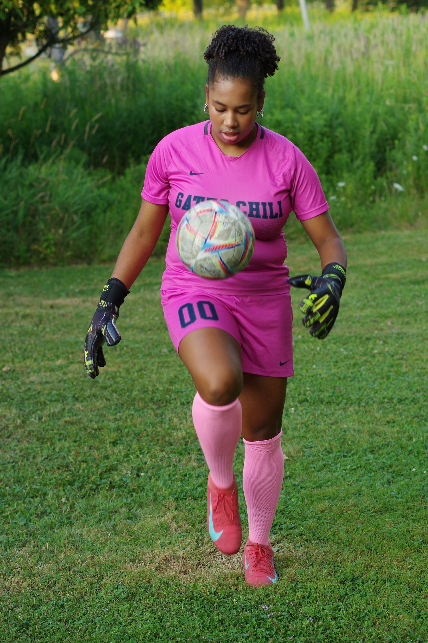 Person in pink athletic wear practicing soccer moves on a grassy field.