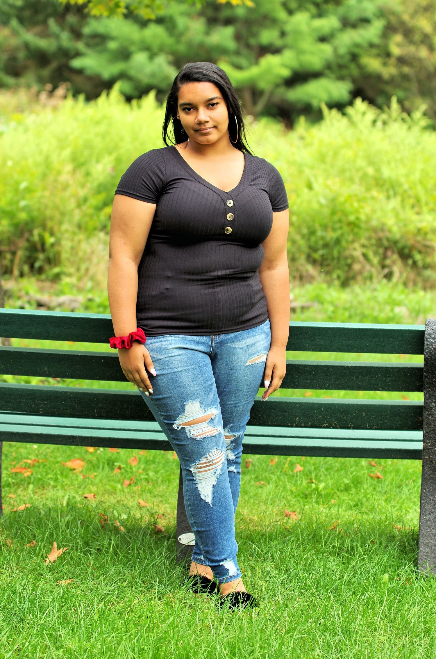 A portrait on a green park bench surrounded by vibrant summer foliage.