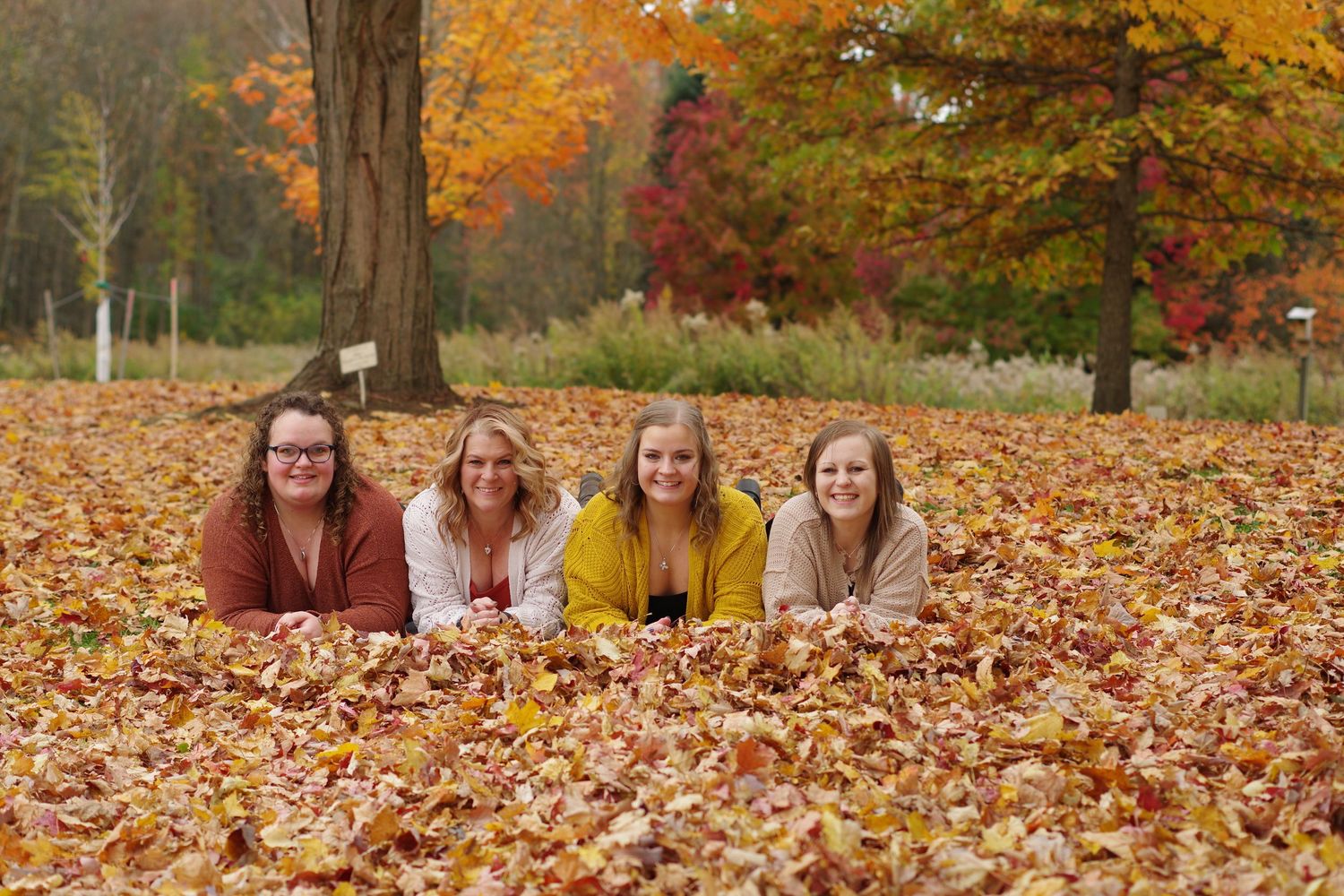 Four people lying in autumn leaves during fall photo session outdoors.