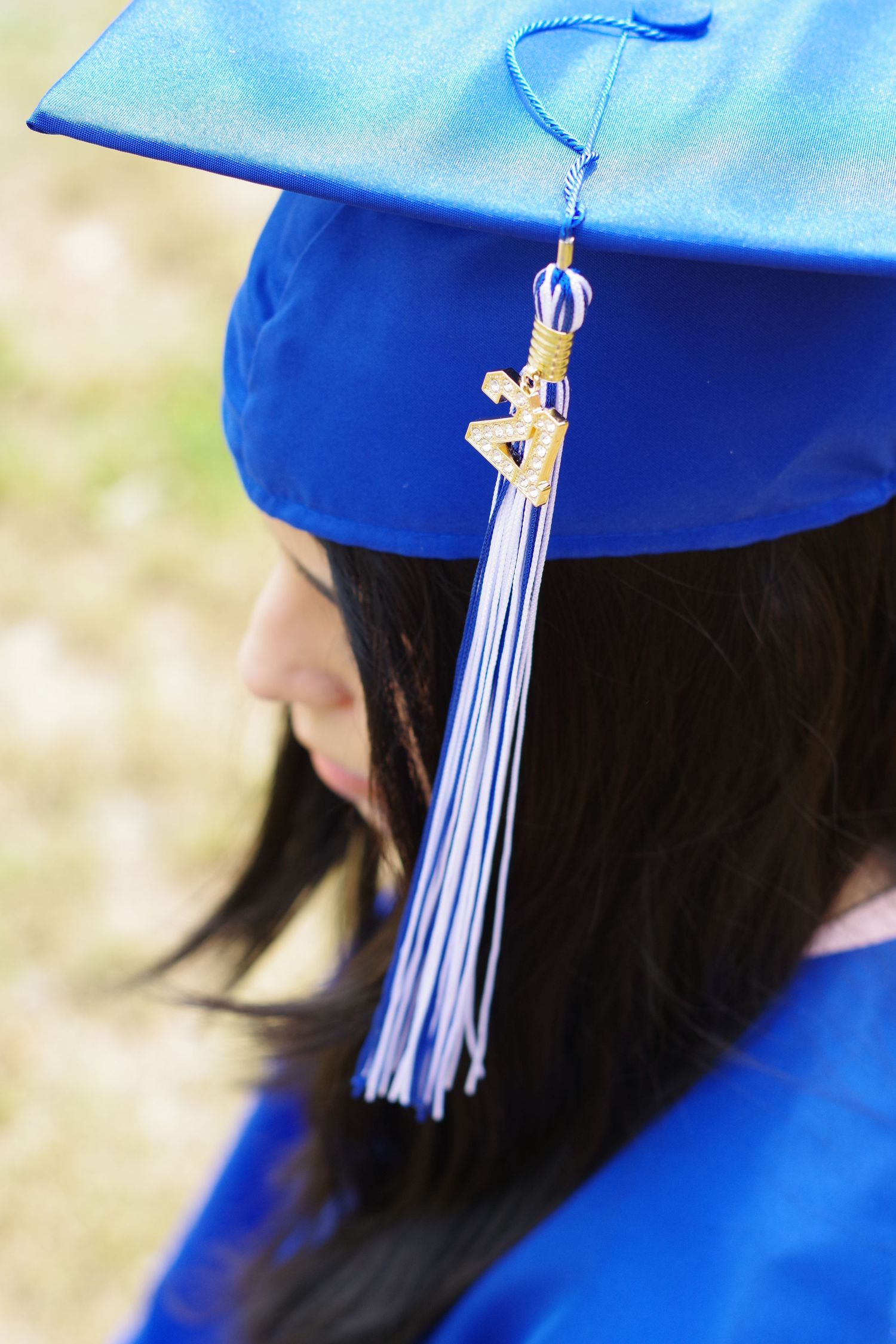 Close-up detail of blue graduation cap with white and blue tassel.