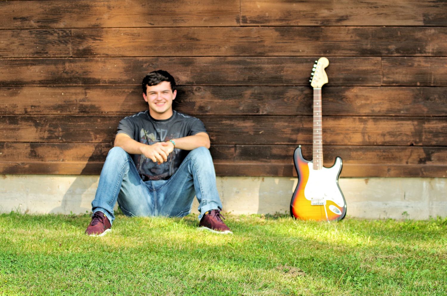 Casual outdoor portraits against rustic wooden wall with guitar visible in background.
