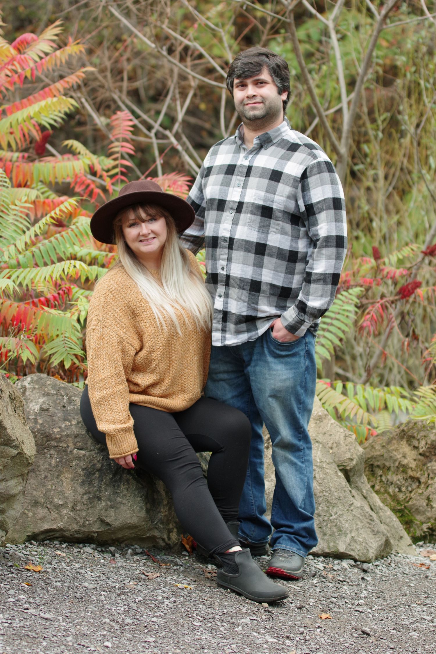 Casual autumn photoshoot on rocky terrain with fall foliage in background.