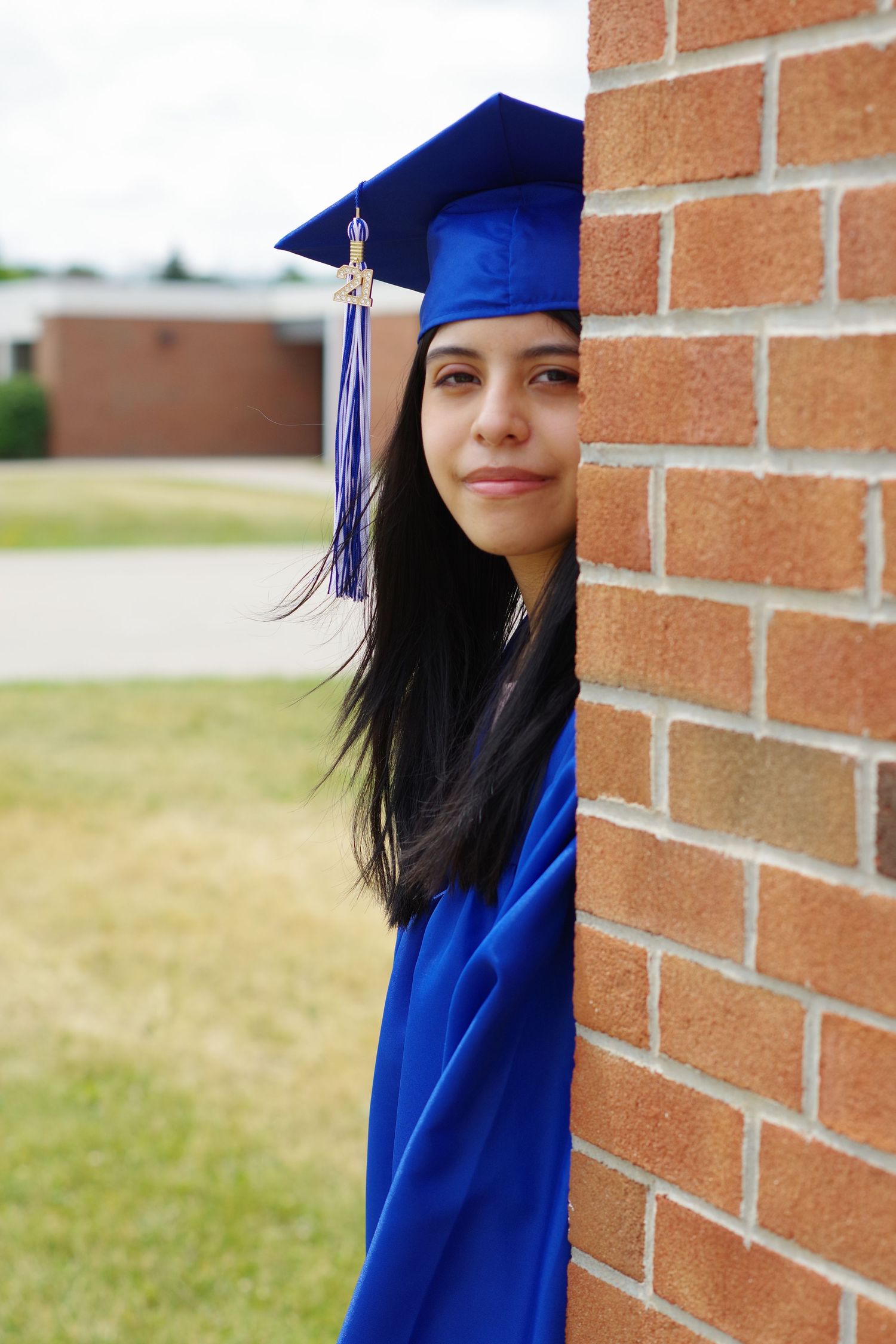 Side profile graduation photo next to brick wall in royal blue regalia.
