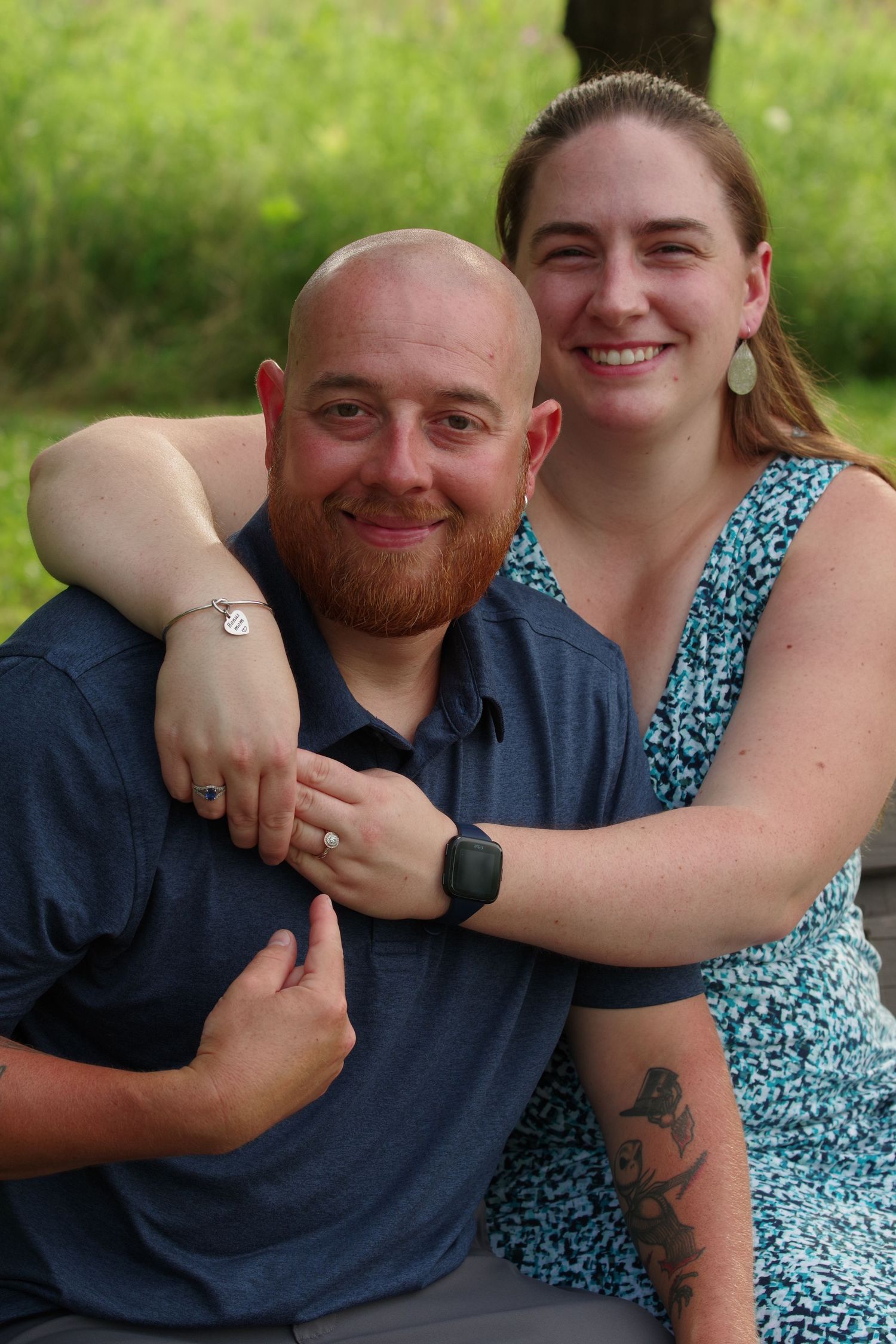 Intimate portrait of couple outdoors showing jewelry and tattoo details.