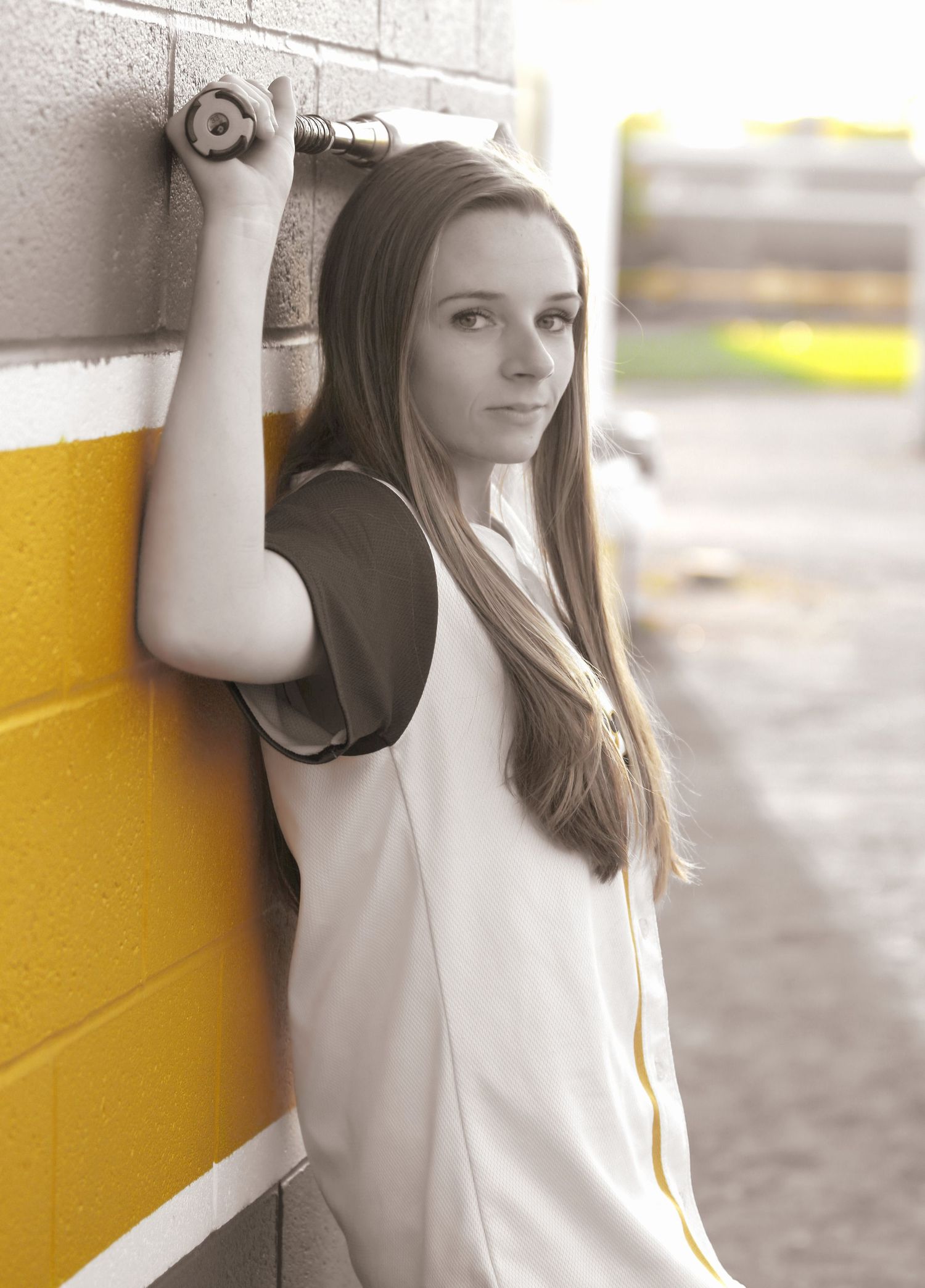 Casual portrait against yellow and white painted wall with long hair and white top in soft lighting.