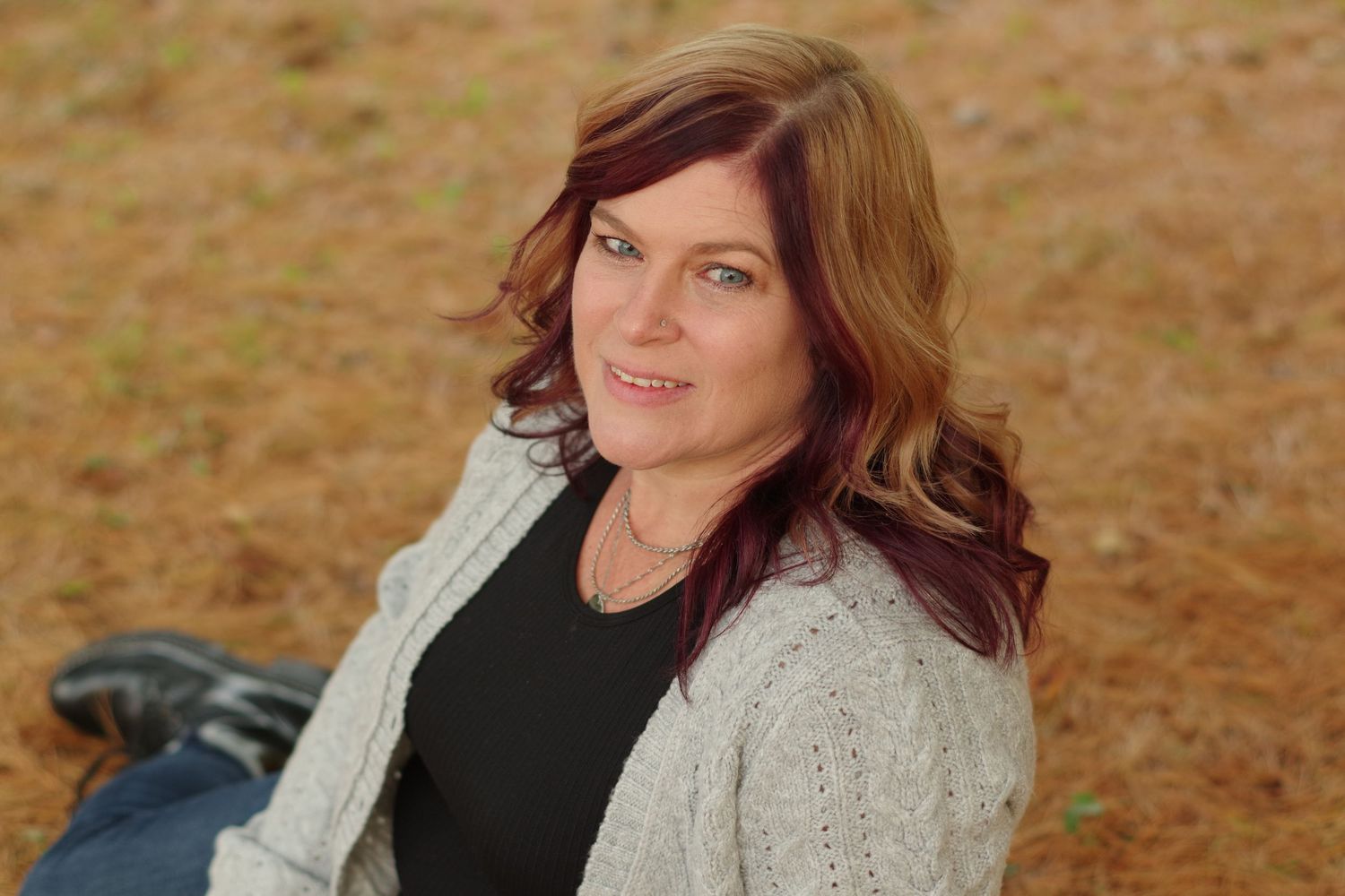 Portrait shot of person in beige cardigan against warm fall backdrop.