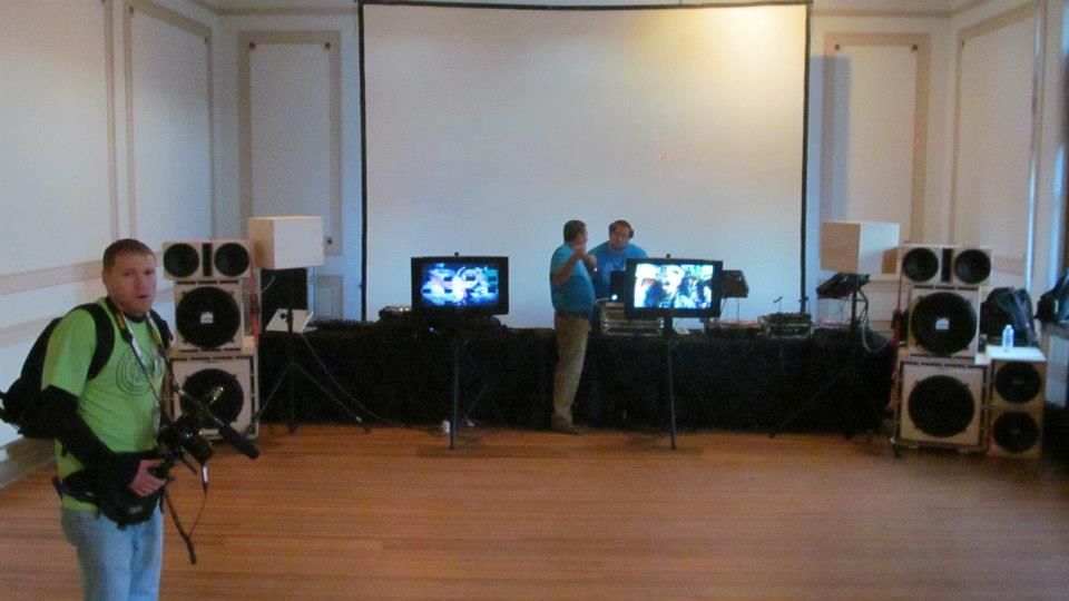 Event attendees in a dimly lit room displaying small framed artwork at what appears to be a gathering.