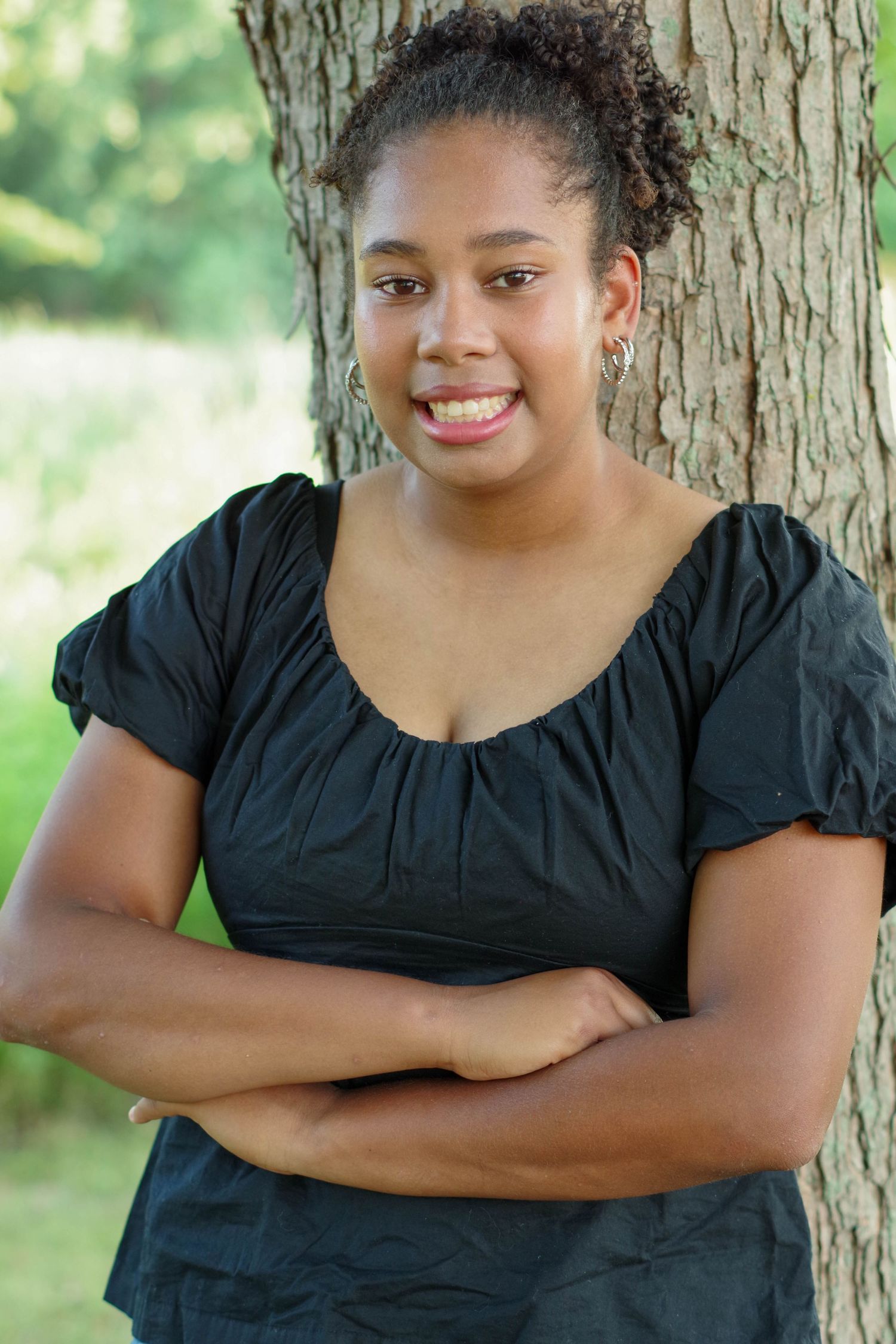 Person in black top leans against tree trunk in outdoor portrait series with varying expressions and poses.