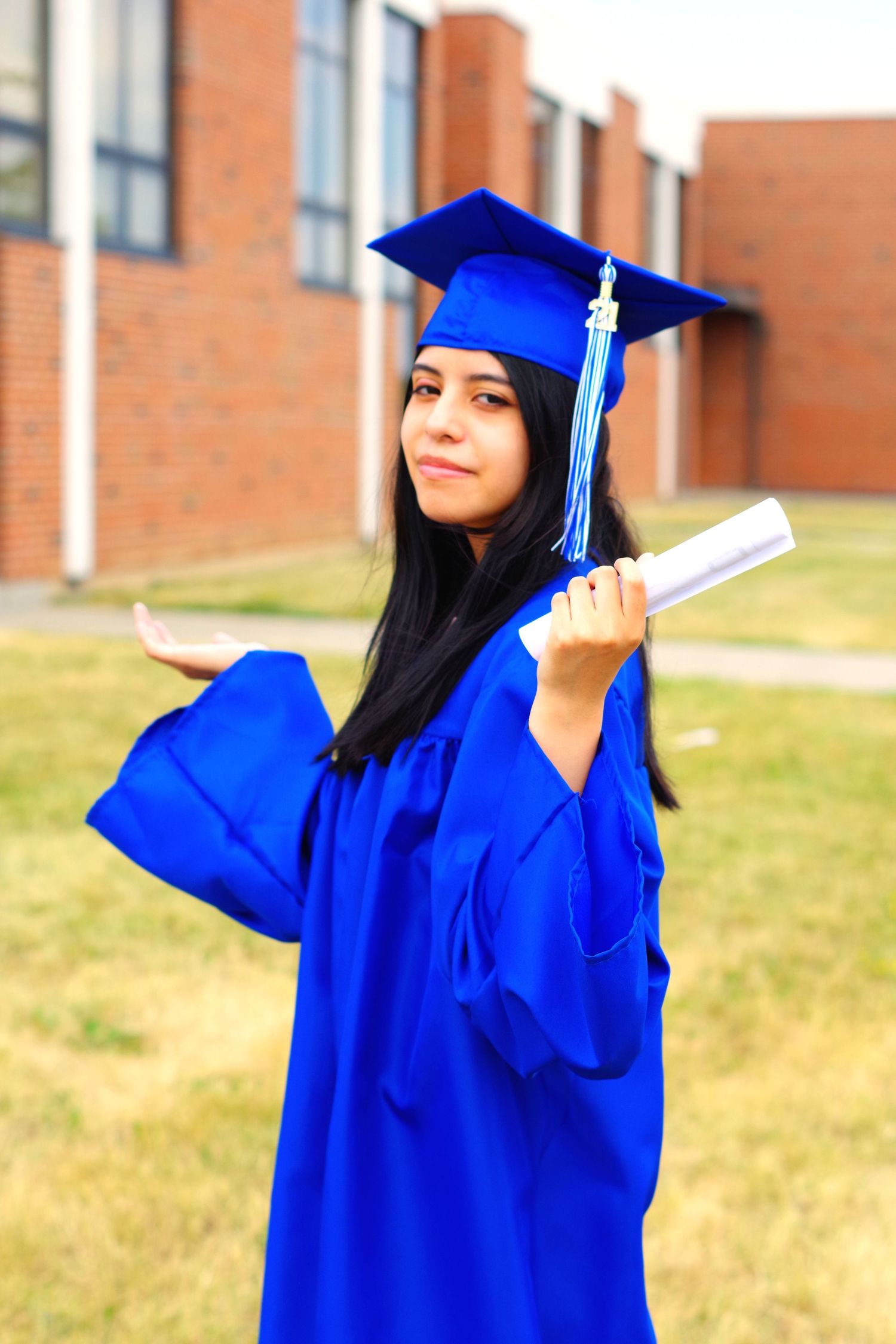 Playful graduation poses captured outdoors in bright blue academic regalia.